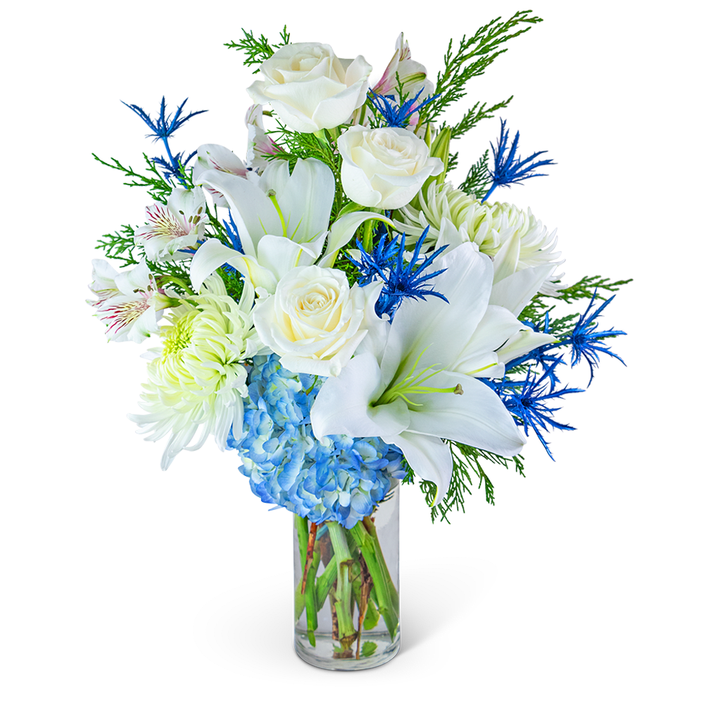 White roses, lilies, and blue hydrangeas in a clear glass vase