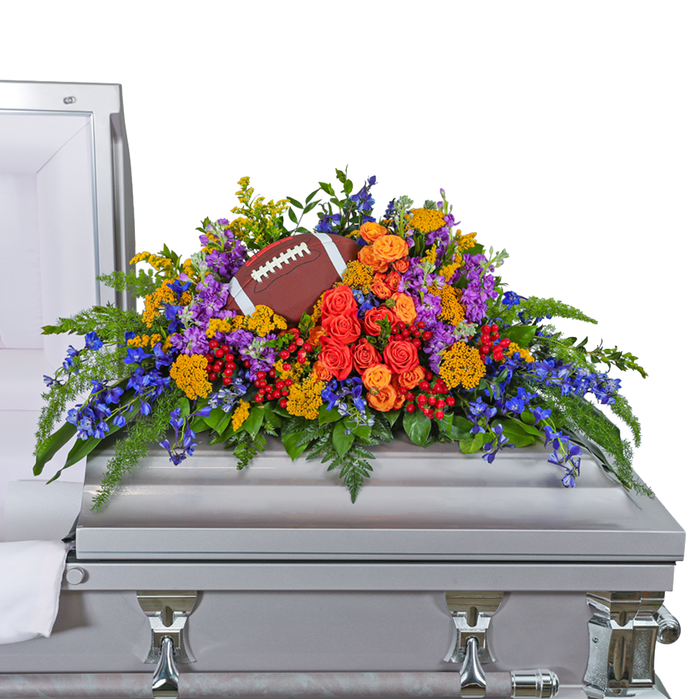 Tears in Heaven Personalized Casket Spray - Our Tears in Heaven Personalized Casket Spray is a stunning arrangement filled with Roses, Delphinium, Stock, Yarrow, Solidago, Hypericum Berries, and other premium foliage. Vibrant colors symbolize warmth and a personalized touch can be added, honoring your loved one's unique passions. This heartfelt tribute captures their joyful spirit and the lasting impact they have made to those around them. **The sports equipment shown in the picture is not part of the design but is shown to demonstrate how the design can be personalized.**