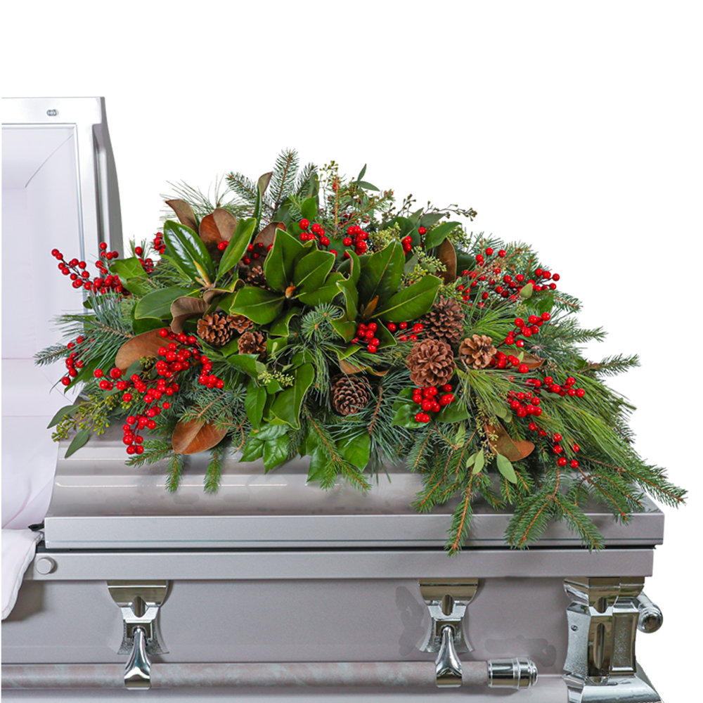 Spirit in the Sky Casket Spray - Our Spirit in the Sky Casket Spray is a captivating memorial arrangement adorned with magnolia, eucalyptus, assorted evergreen, pine, red berries, and pinecones. The deep green hues and natural elements evoke a sense of tranquility and connection to the beauty of the forest. This casket spray serves as a peaceful and timeless tribute, honoring your loved one with the serenity of a woodland sanctuary.
