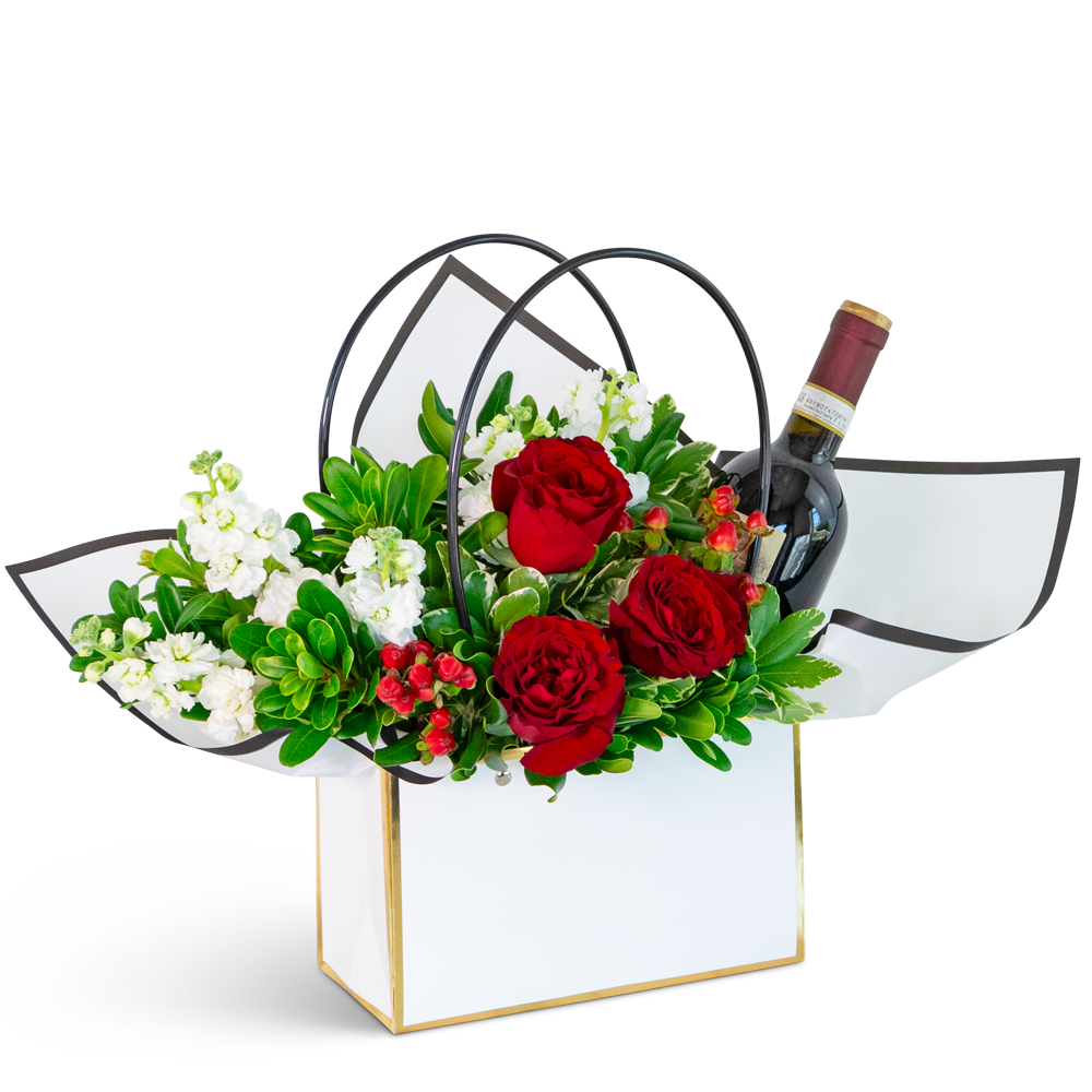 Red roses and white flowers in a gift box with a wine bottle