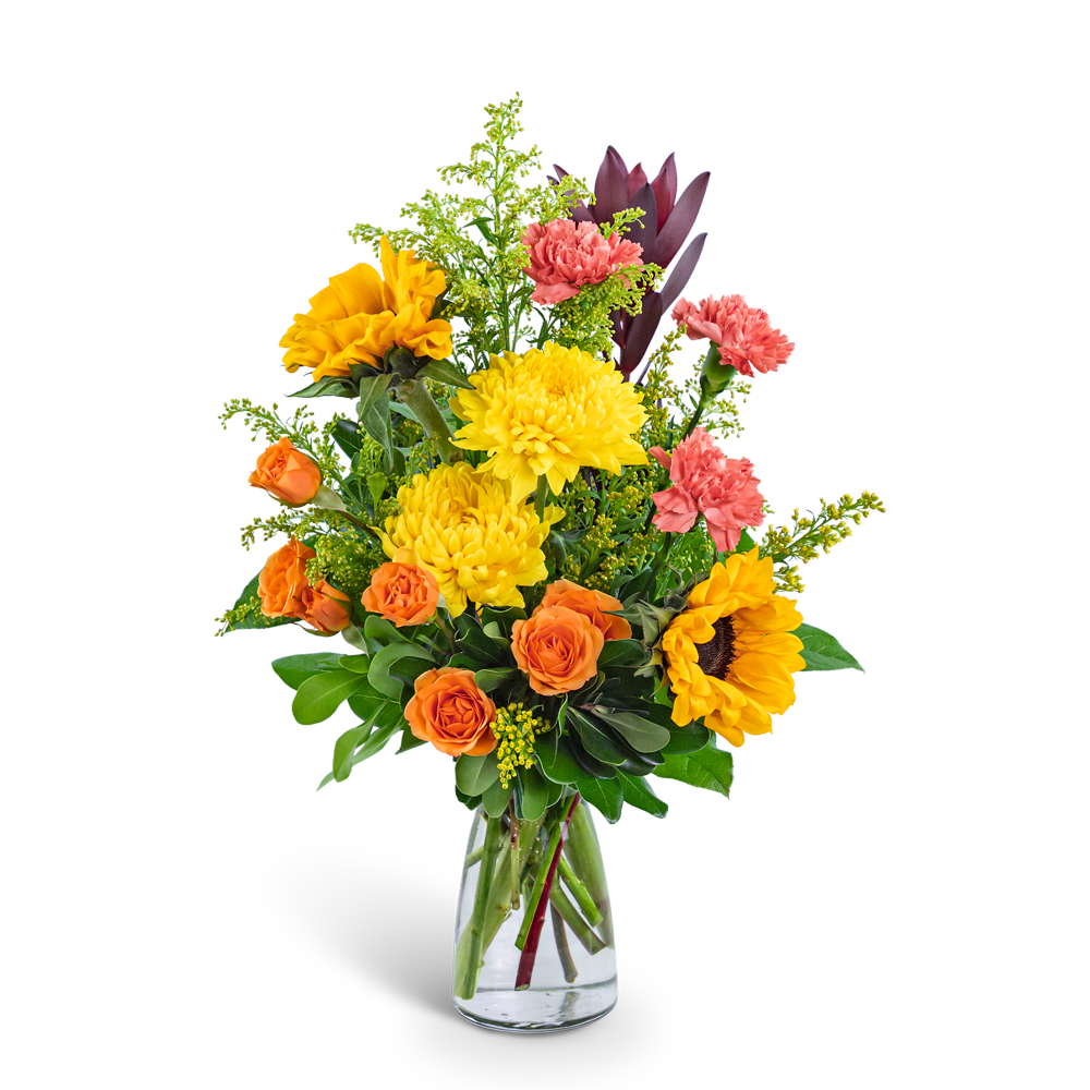 Bouquet of yellow sunflowers, orange roses, and pink carnations in a clear glass vase