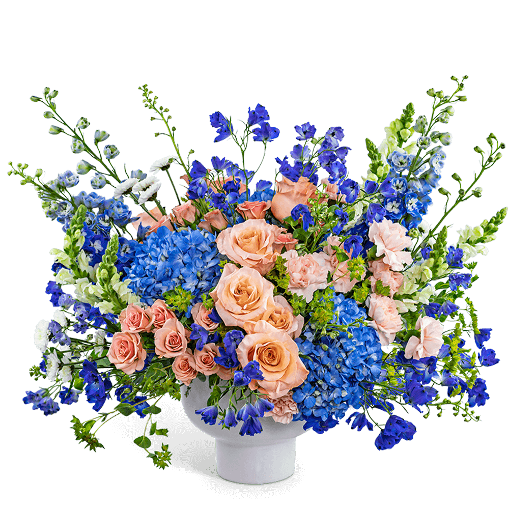 Peach roses and blue flowers in a white vase