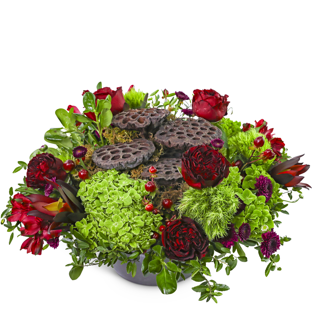 Red and green floral arrangement with lotus pods in a low bowl