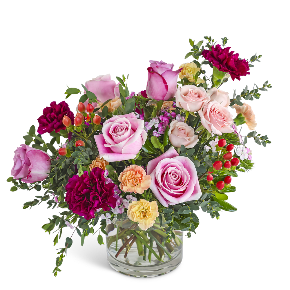 Mixed arrangement of pink roses, dark red carnations, and peach blooms in a clear glass vase