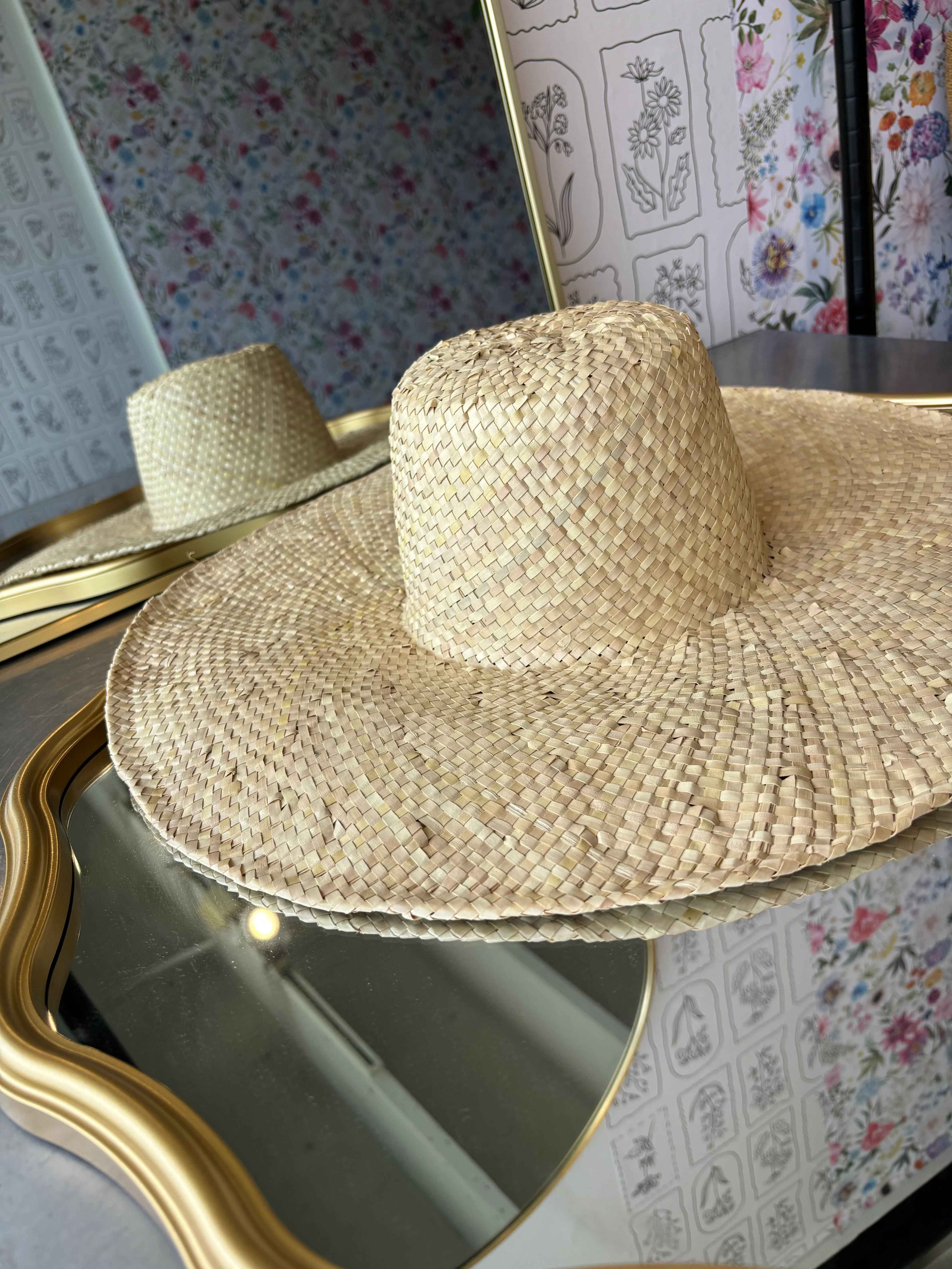 Two woven straw hats on a mirrored surface