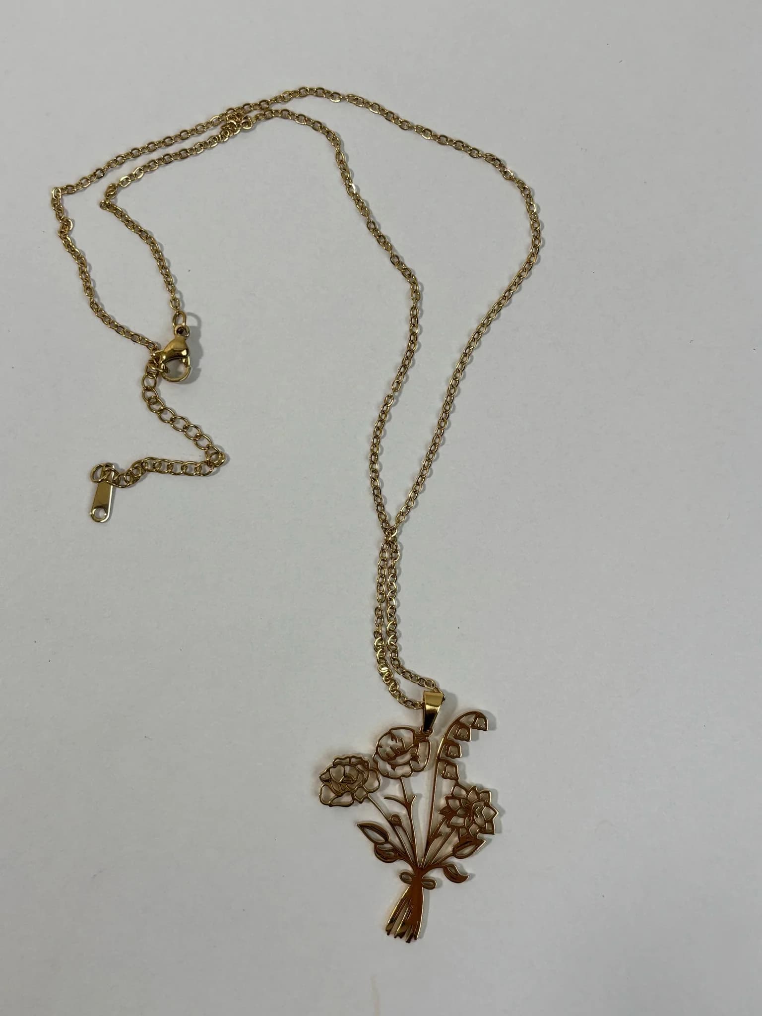 Gold-tone necklace with a floral pendant on a plain background