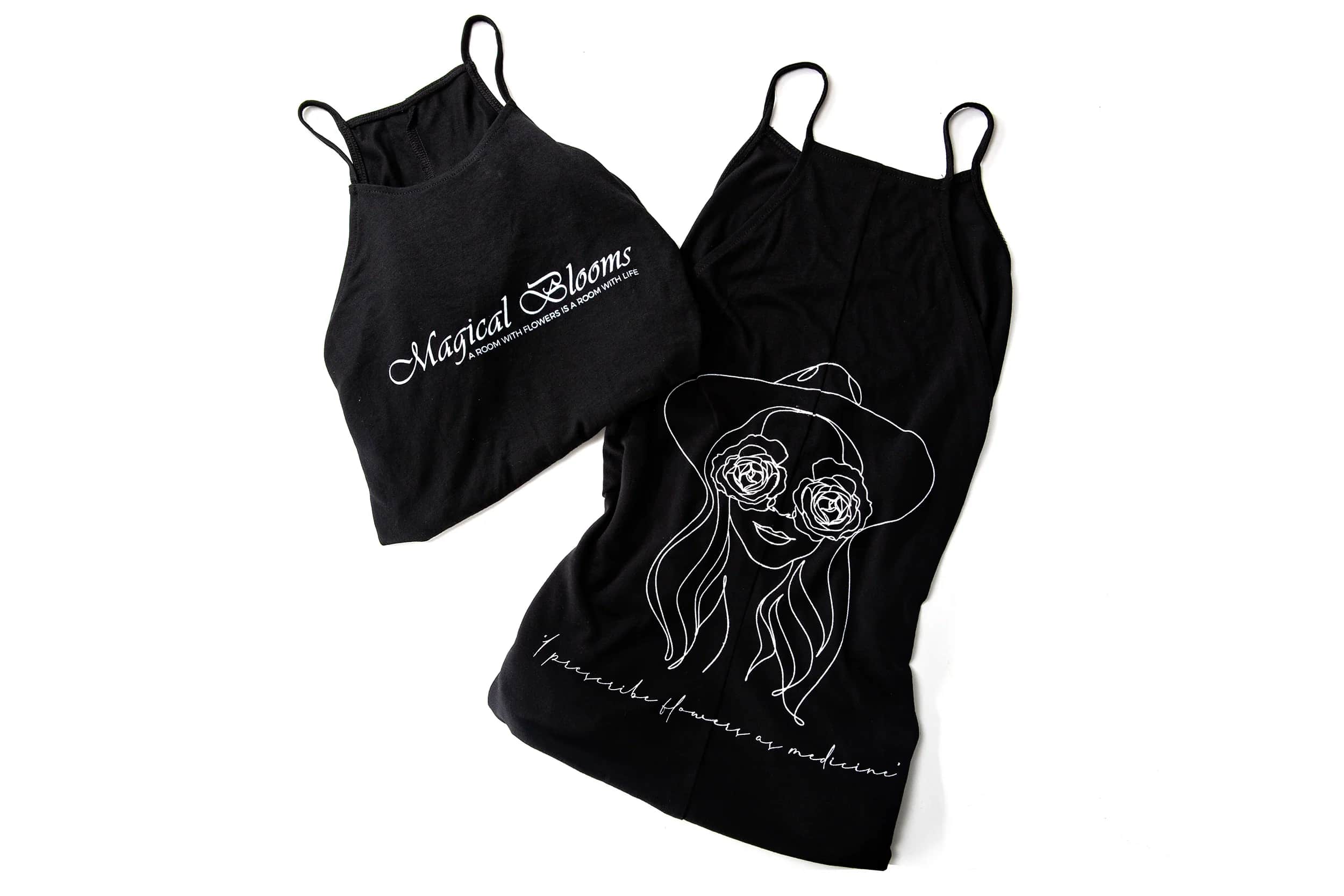 Two black floral-print tank tops with white line art and text