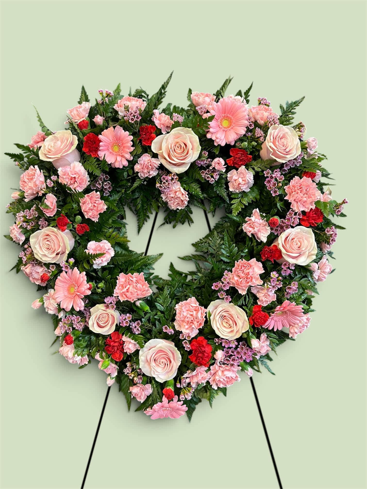 Heart-shaped floral wreath with pink roses, carnations, and daisies