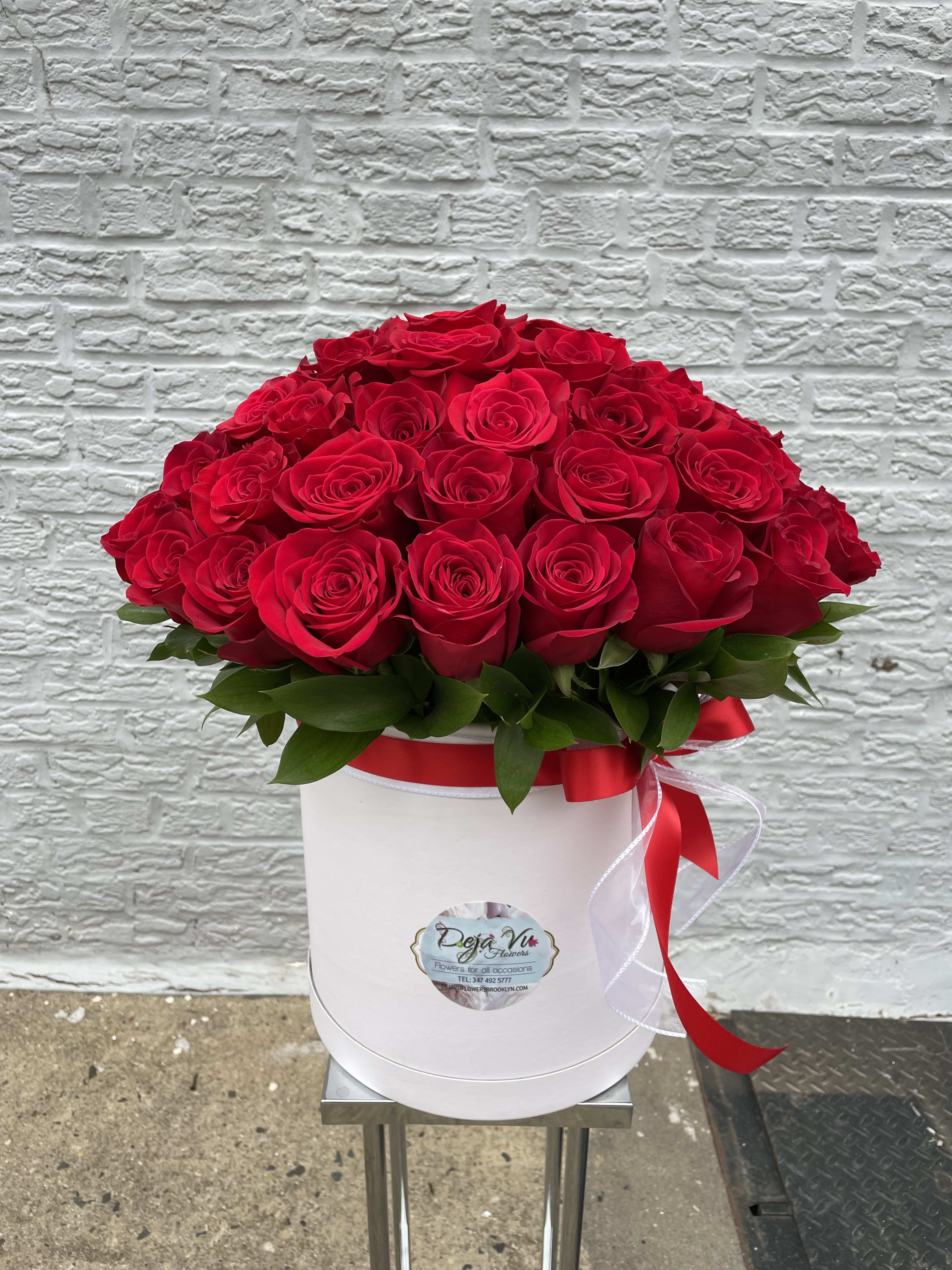 Red roses arranged in a white hat box with a red ribbon
