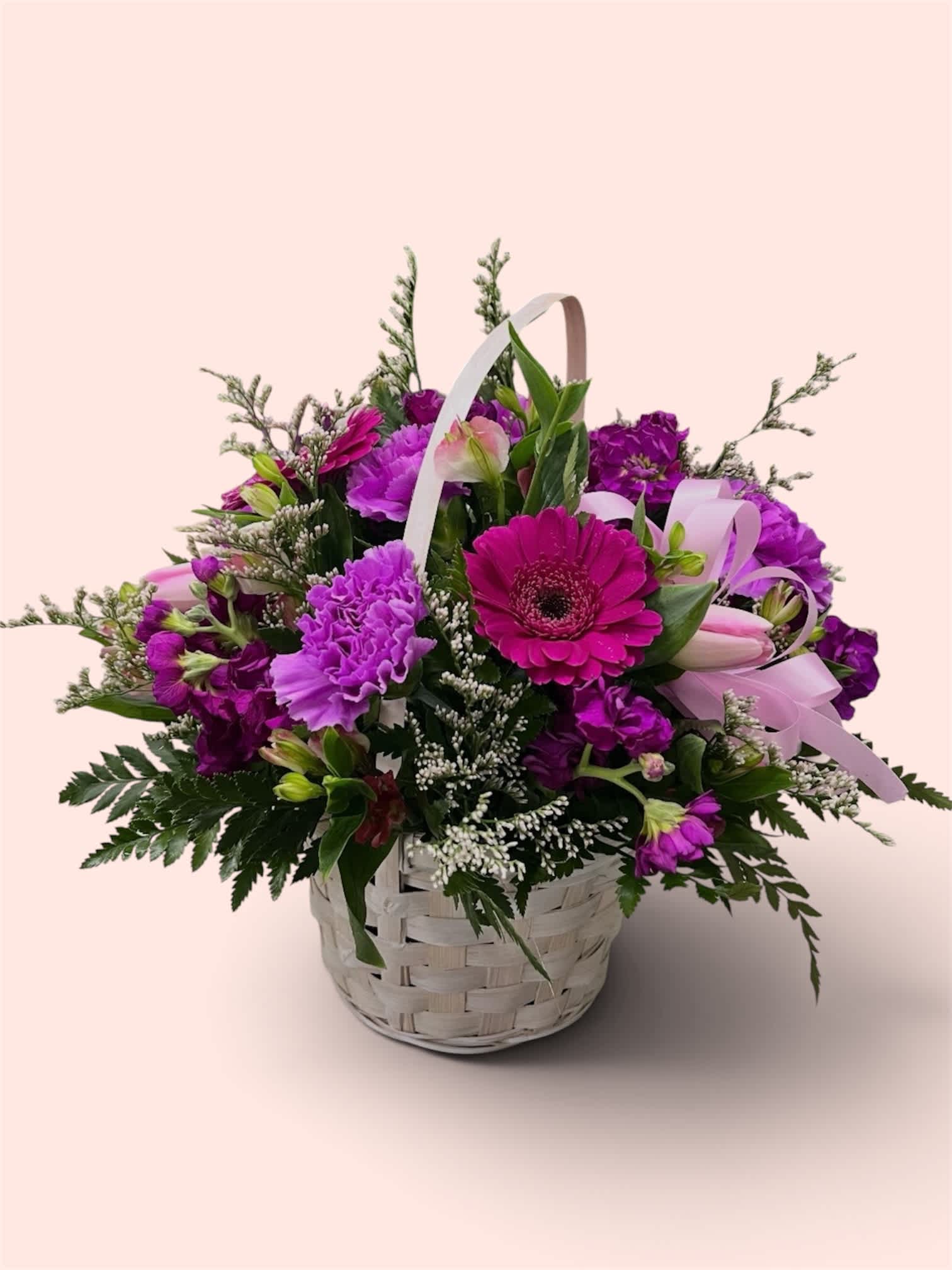 Basket of purple flowers with a pink gerbera daisy and ribbon