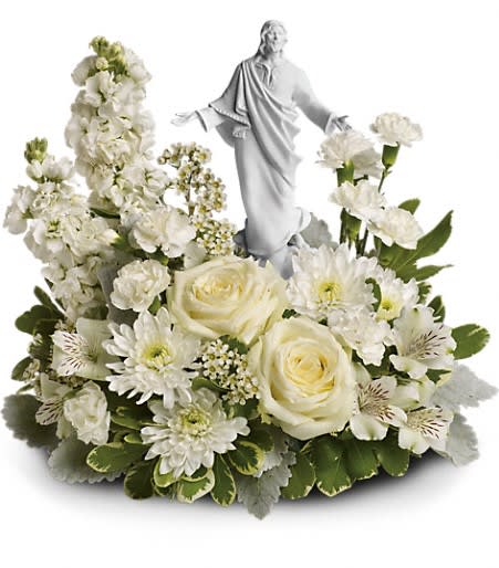 White floral arrangement with a small statue of Jesus at the center