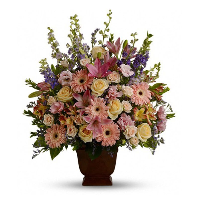 Loving Grace - Fresh flowers such as peach and light pink roses, lavender and purple larkspur, pink asiatic lilies, alstroemeria, gerberas and lisianthus are set in an urn container  Approximately 26" W x 30" H      Orientation: One-Sided