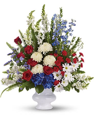 Red roses, white mums, blue flowers, and white daisies in a white vase