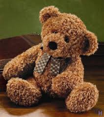 Brown teddy bear with a checkered ribbon sitting on a wooden surface