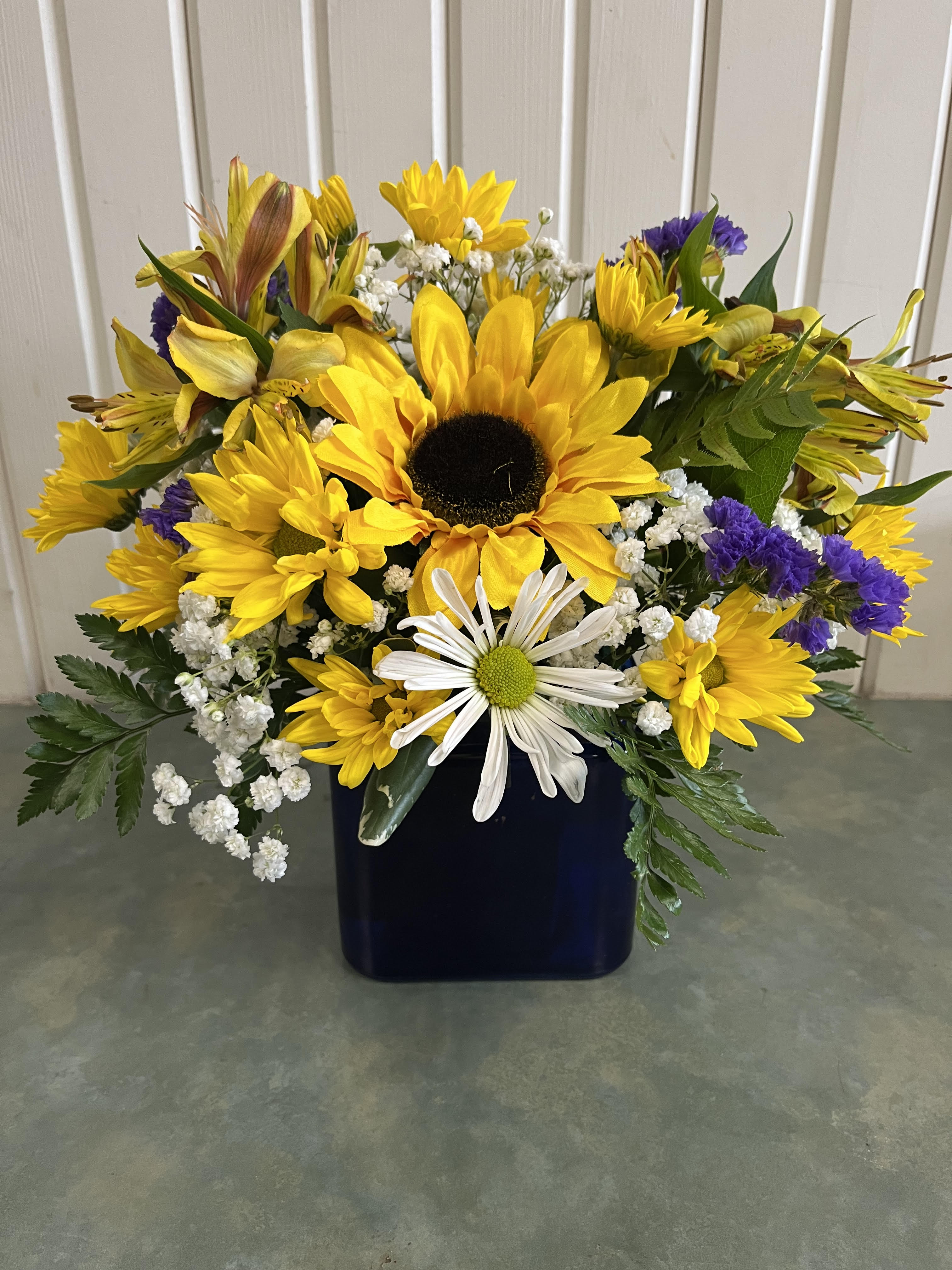 Sunflower and daisy bouquet in a dark blue vase