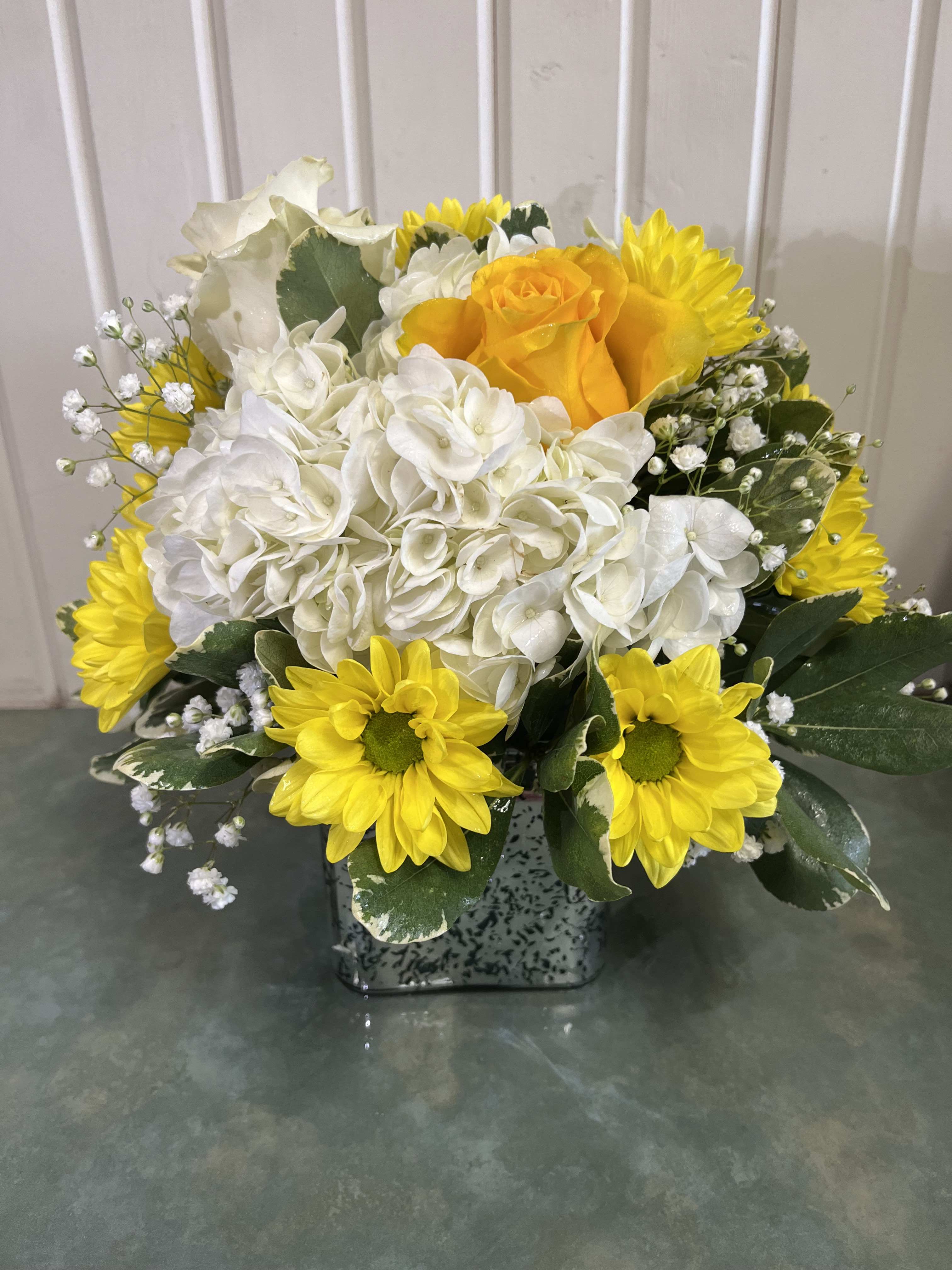 Yellow daisies and white hydrangeas in a square vase