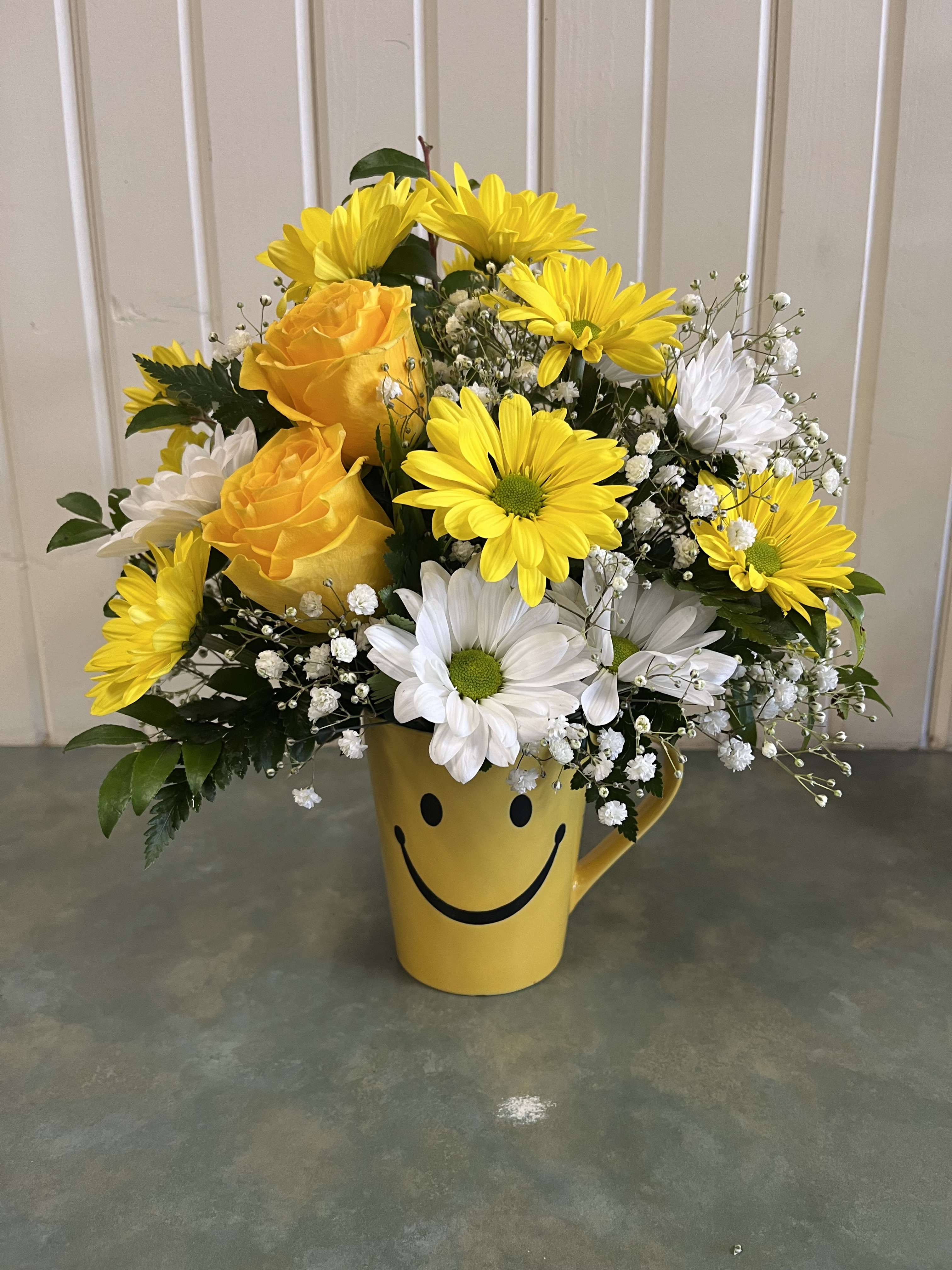 Yellow and white flowers arranged in a smiley-face mug vase