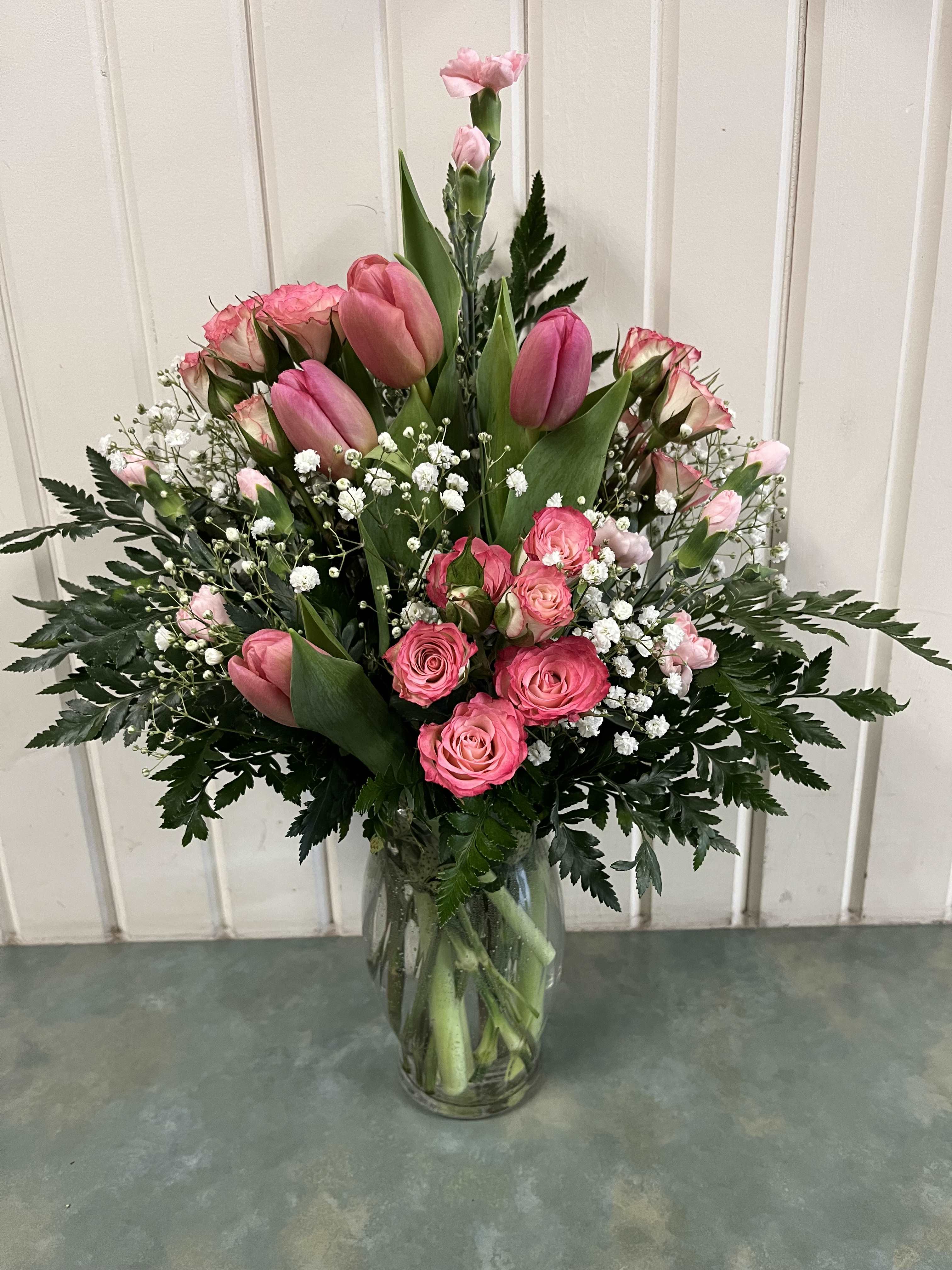 Pink tulips and roses arranged in a clear glass vase