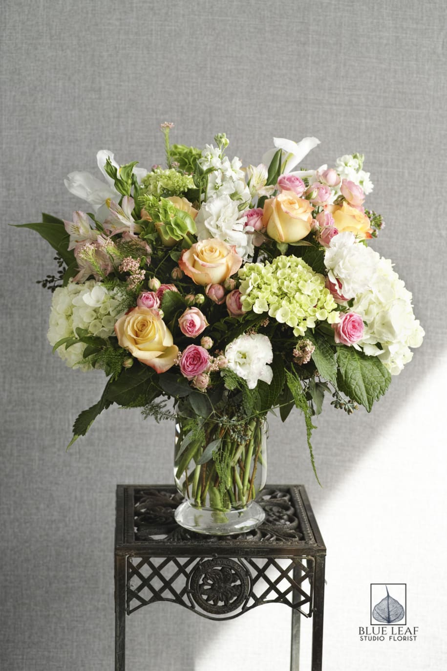 Mixed bouquet of roses, hydrangeas, and white blooms in a glass vase