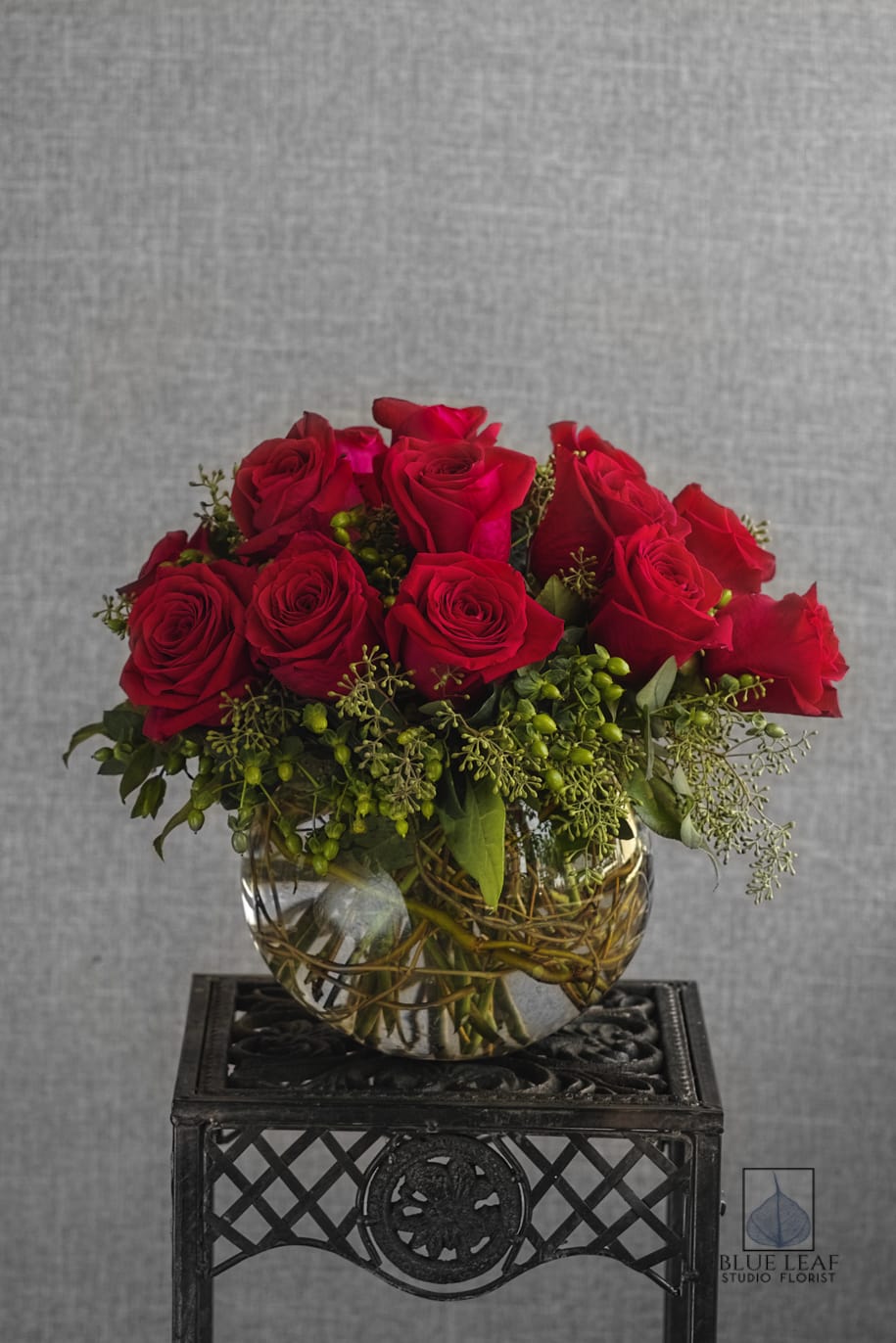 Red roses arranged in a clear glass bowl vase