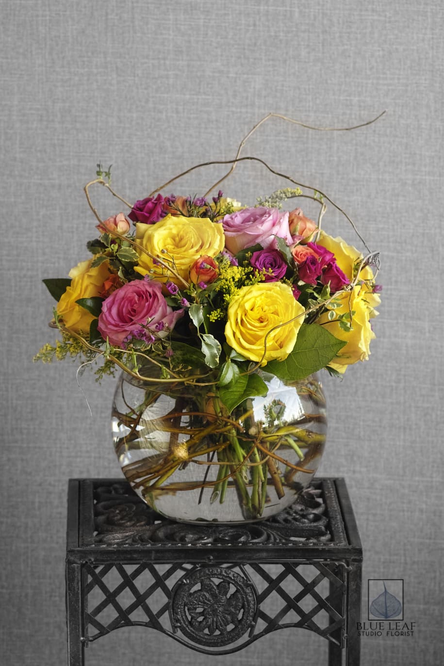 Mixed roses in a clear glass vase with curly branches