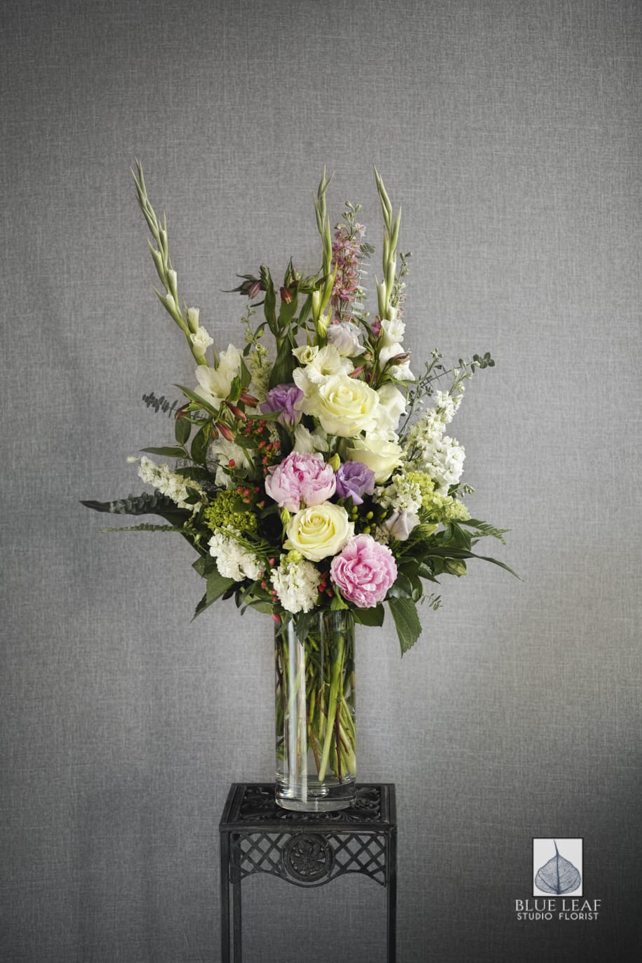 Tall floral arrangement in a clear glass vase with pink, white, and lavender blooms