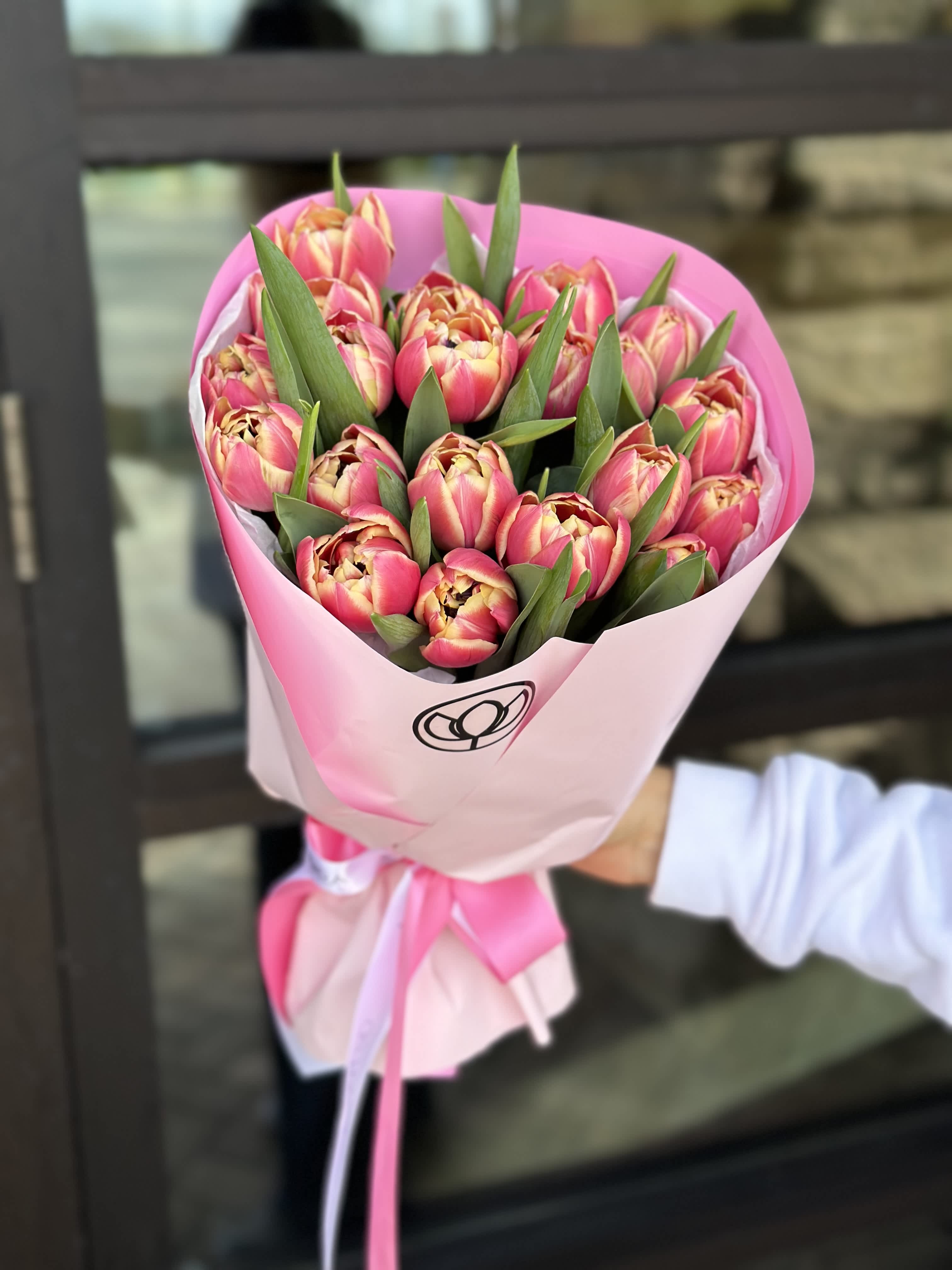 Bouquet of pink tulips wrapped in pink paper with a ribbon