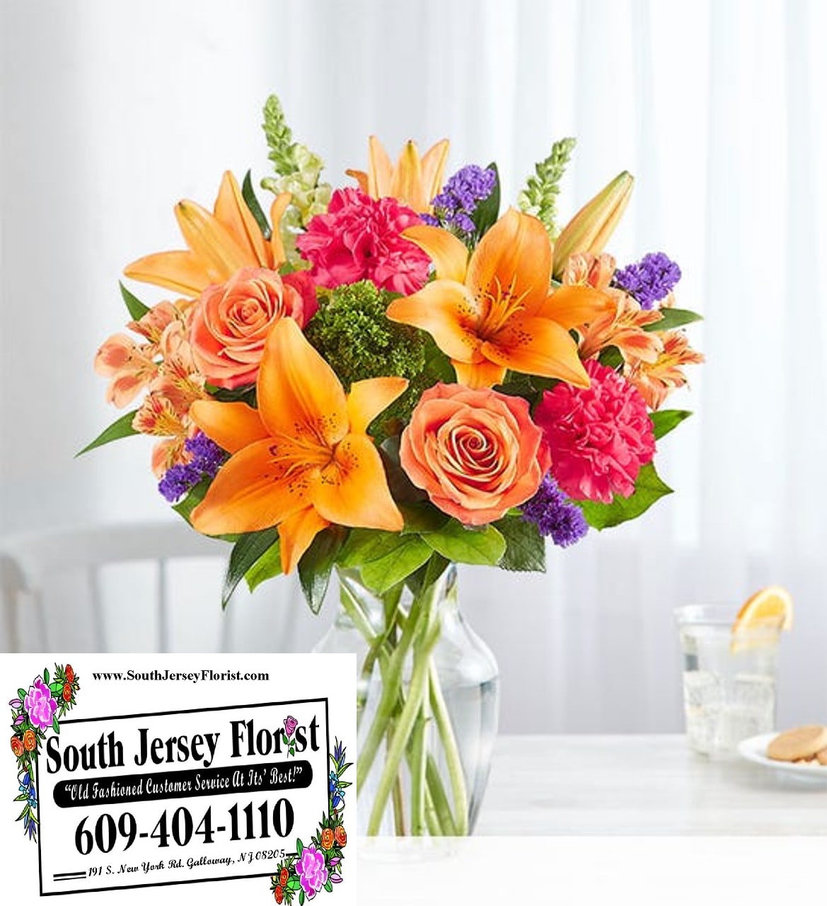 Bouquet of orange lilies, peach roses, and pink carnations in a glass vase