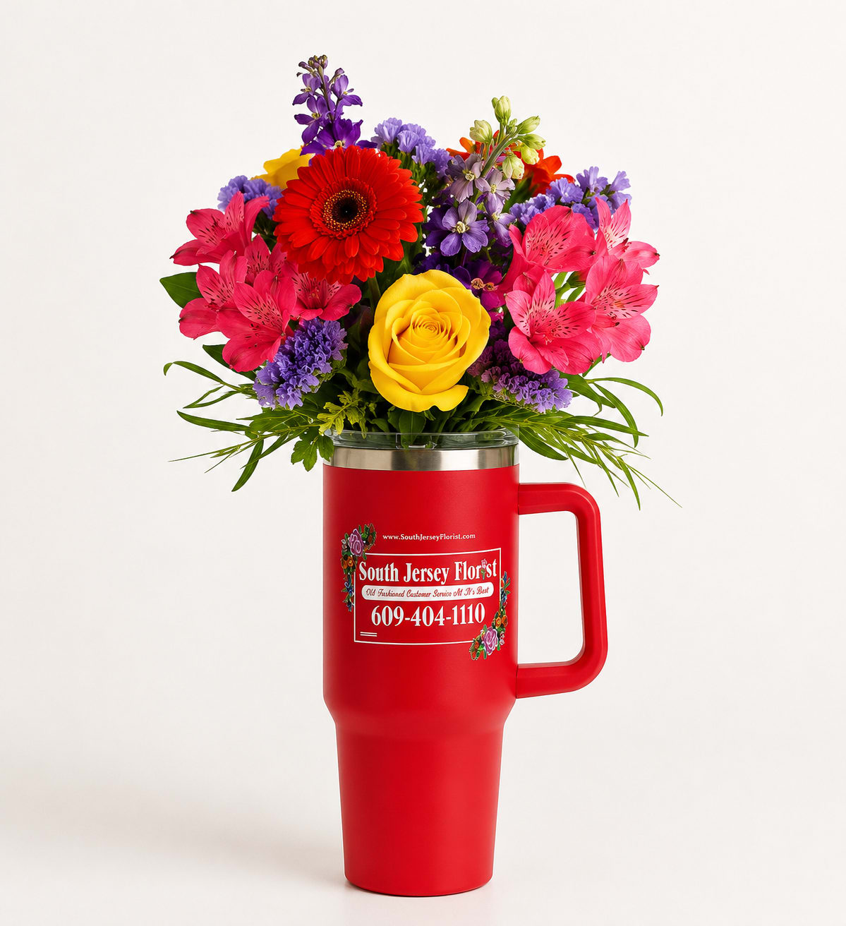 Crimson Celebration™ Tumbler Bouquet - Bright, cheerful, and made to be enjoyed long after the flowers have faded, the Crimson Celebration™ Tumbler Bouquet combines fresh blooms with a reusable South Jersey Florist insulated tumbler. Featuring a vibrant mix of red gerbera daisies, a golden yellow rose, pink alstroemeria, lavender statice, purple stock, and lush greenery, this arrangement is perfect for birthdays, thank-you gifts, get well wishes, congratulations, or simply making someone's day.  Once the flowers have been enjoyed, the premium insulated tumbler becomes a lasting keepsake for coffee, iced drinks, or water—making this gift as practical as it is beautiful.  Perfect For:  Birthdays Thank You Gifts Get Well Wishes Congratulations Just Because Teachers, Nurses &amp; Coworkers