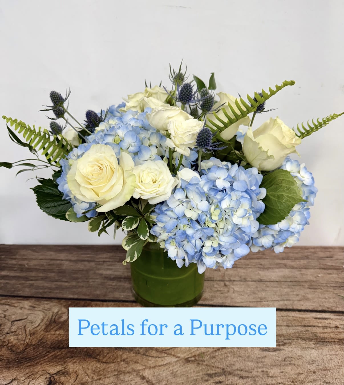 Blue hydrangeas and white roses arranged in a green vase