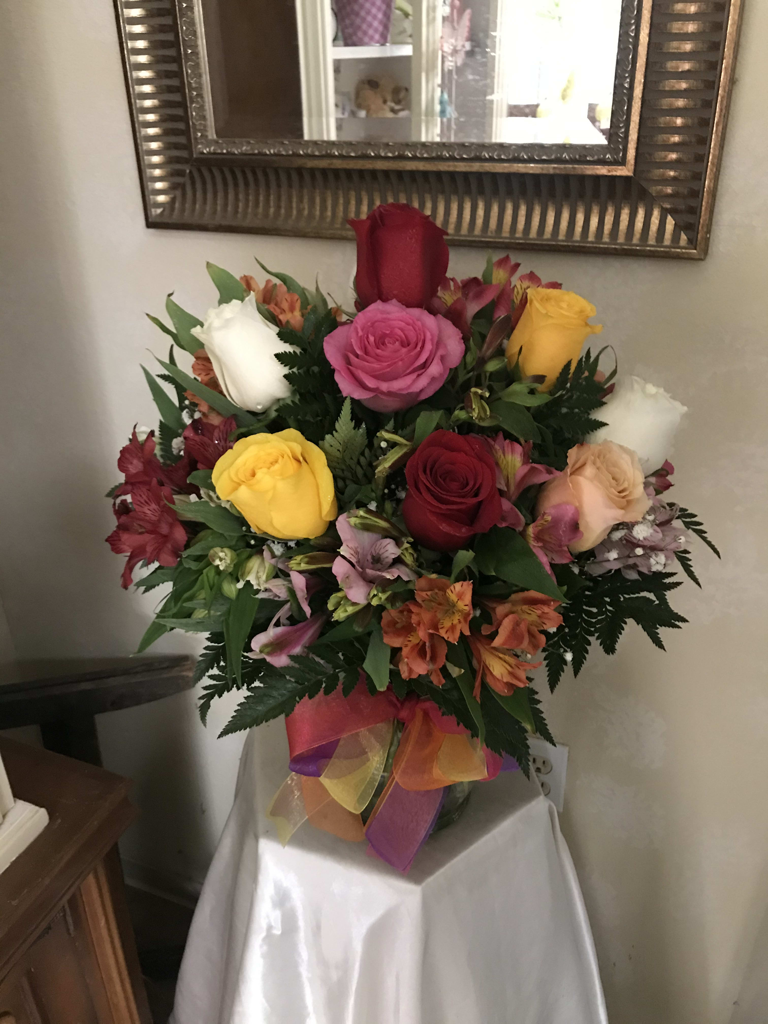 Mixed bouquet of roses and alstroemeria in a vase with a colorful ribbon