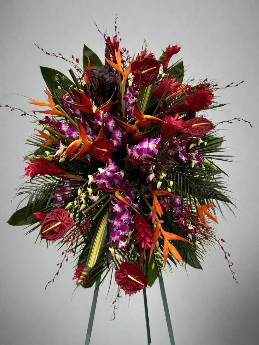 Large tropical standing arrangement with red anthuriums, orchids, and orange bird-of-paradise