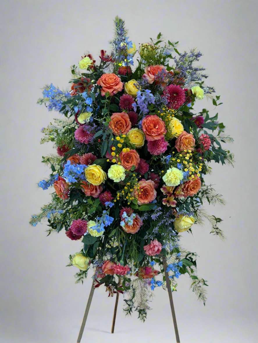 Tall standing floral spray with multicolored roses and mixed blooms