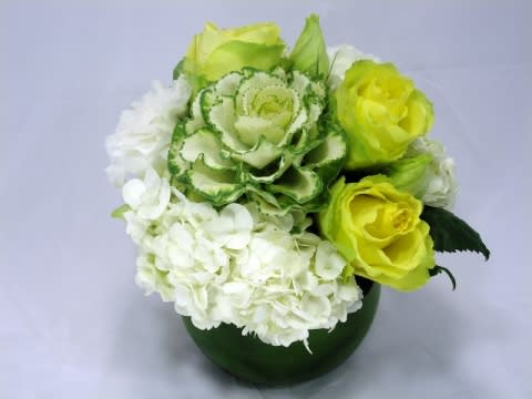 Green and white floral arrangement in a dark green vase