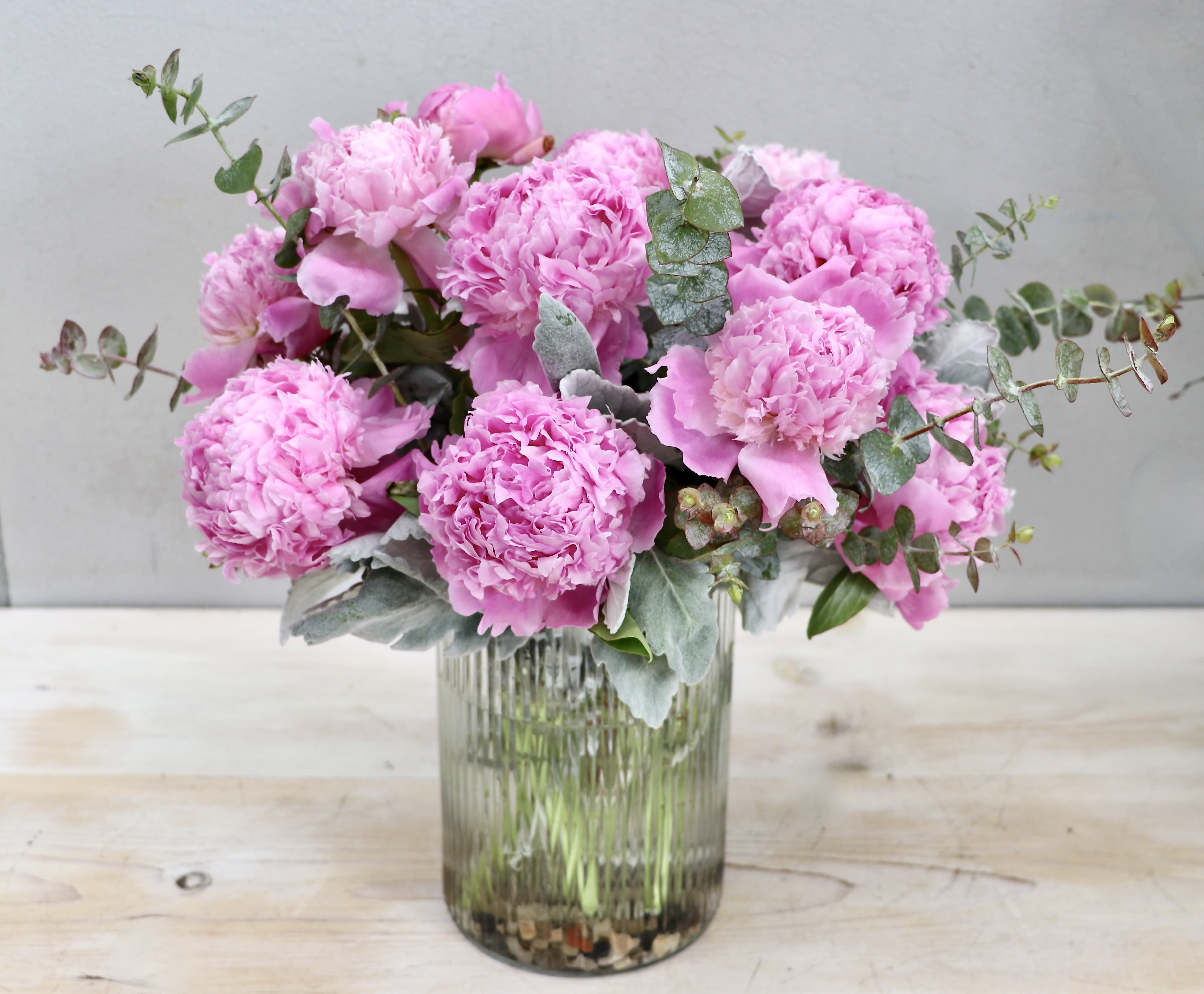 Peony Glow - Glendale Flowers - Lush pink peonies with voluminous, ruffled petals create a soft and romantic display of natural elegance. The arrangement is anchored in a sleek ribbed glass vase, which adds a sophisticated texture and catches the light beautifully. Standard has 12 peonies, deluxe has 20 and premium has 28. 