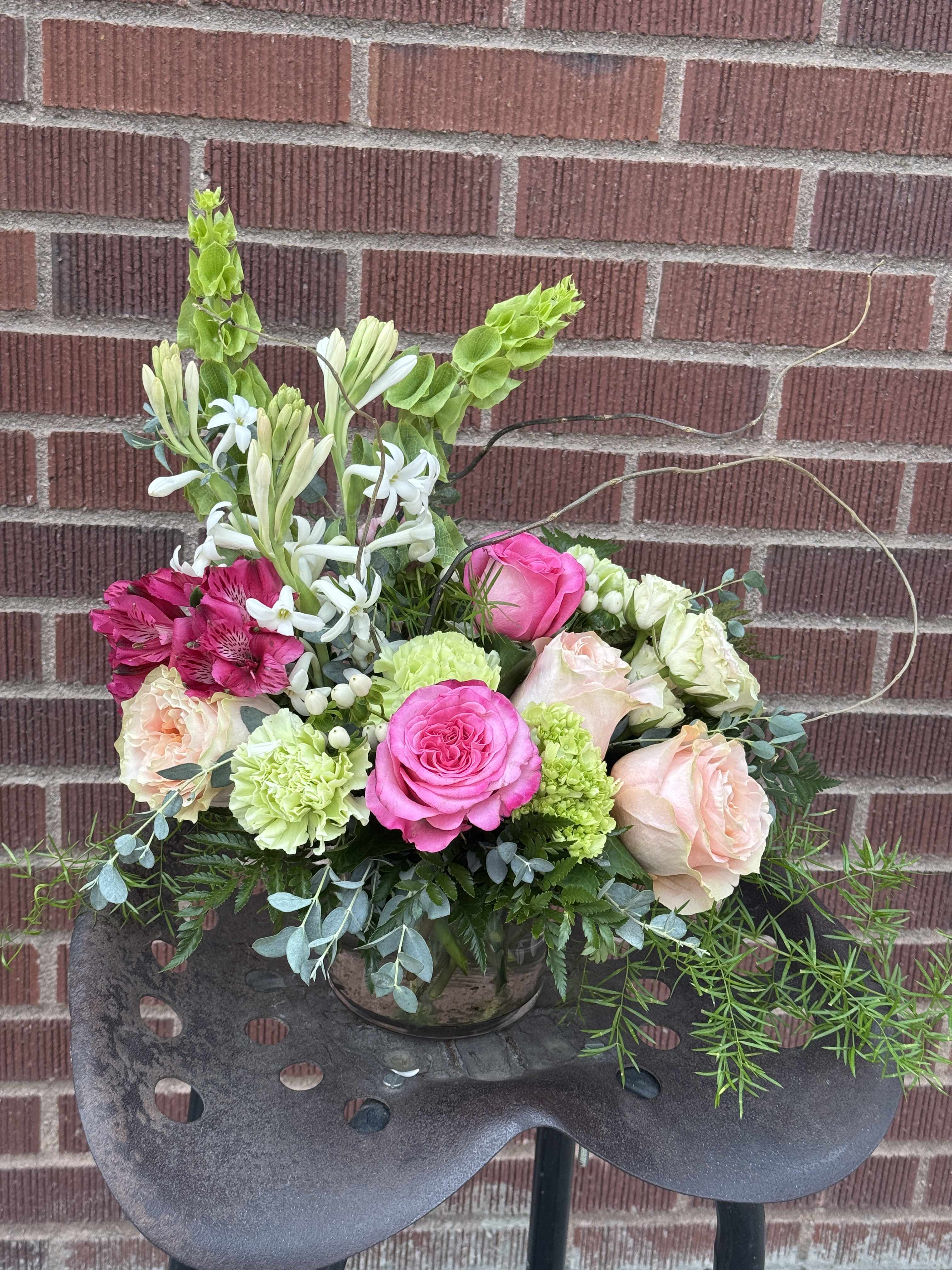 Mixed bouquet in a glass vase with pink, peach, white, and green flowers