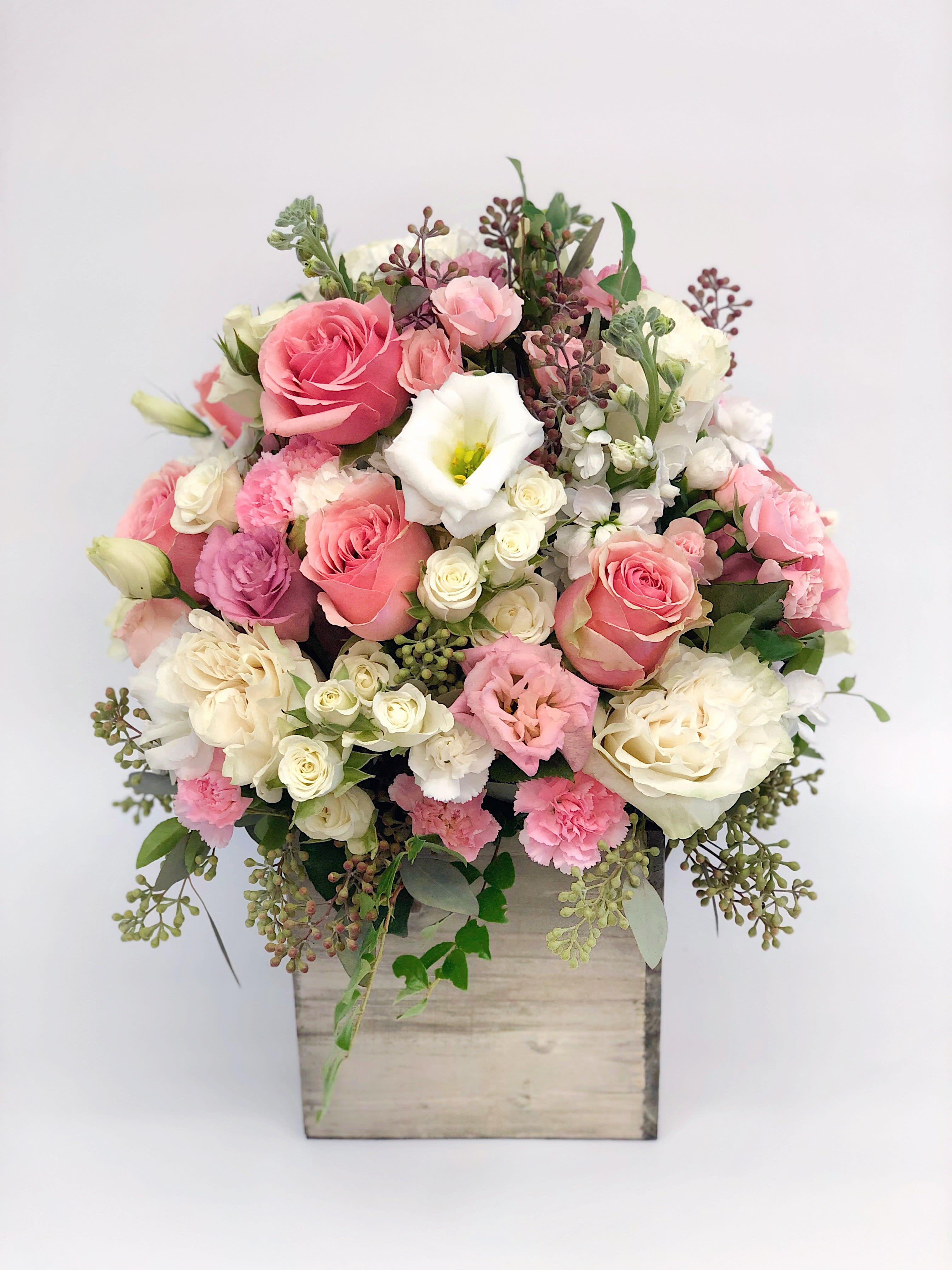 Pink and white rose and carnation arrangement in a rustic wooden box