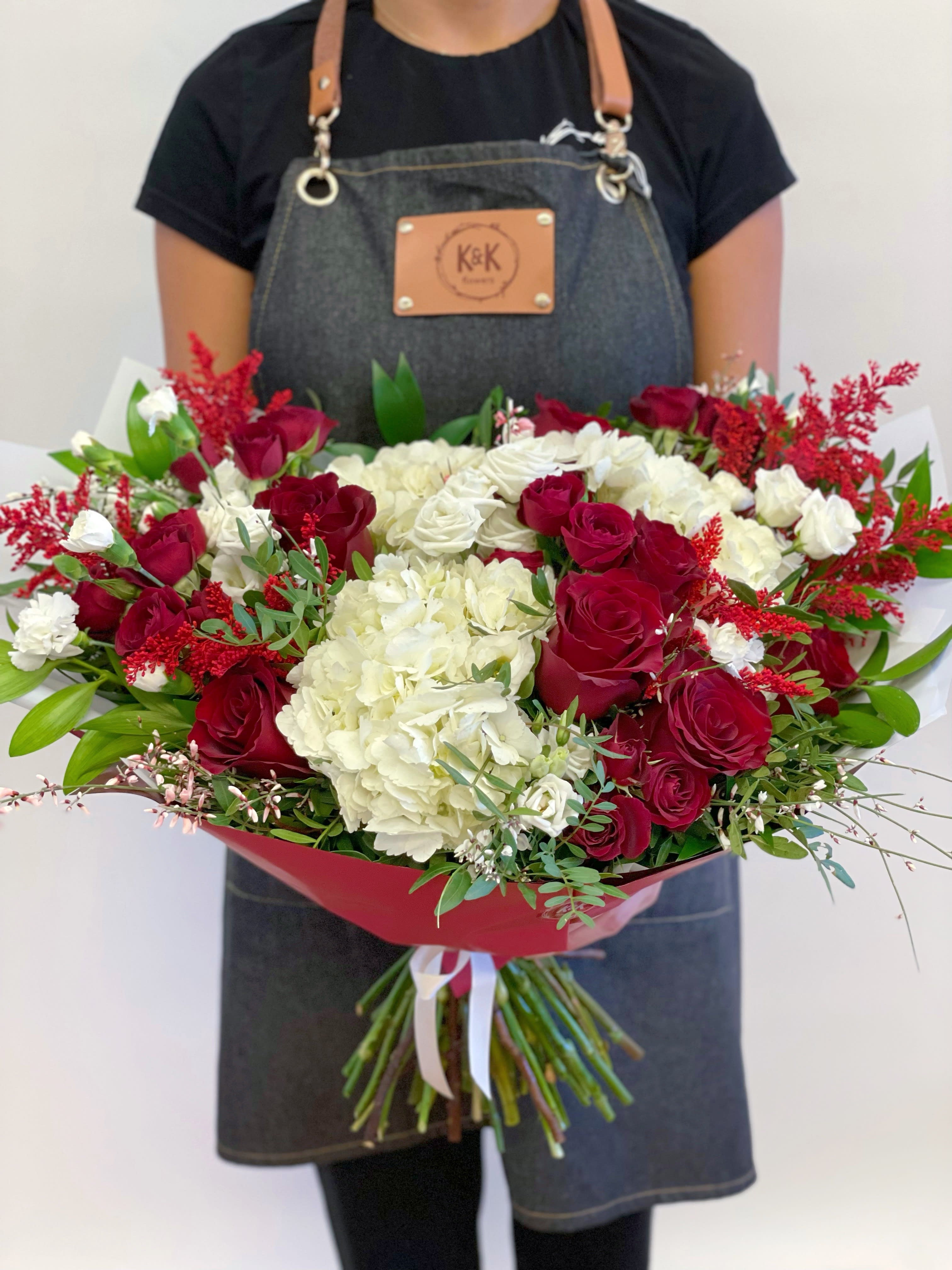 Large bouquet of red roses and white hydrangeas wrapped in red paper