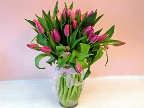 Pink tulip bouquet in a clear glass vase with a sheer ribbon