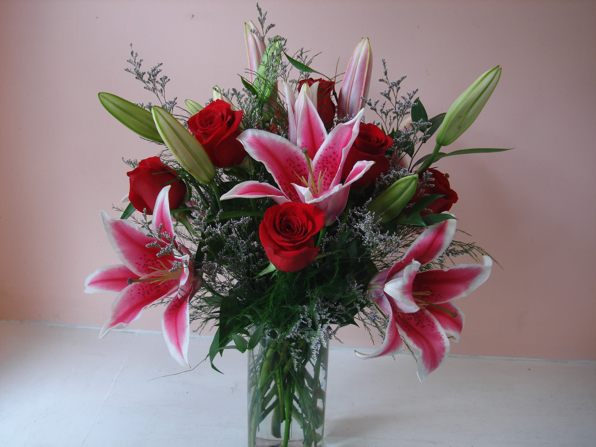 Bouquet of pink lilies and red roses in a clear glass vase