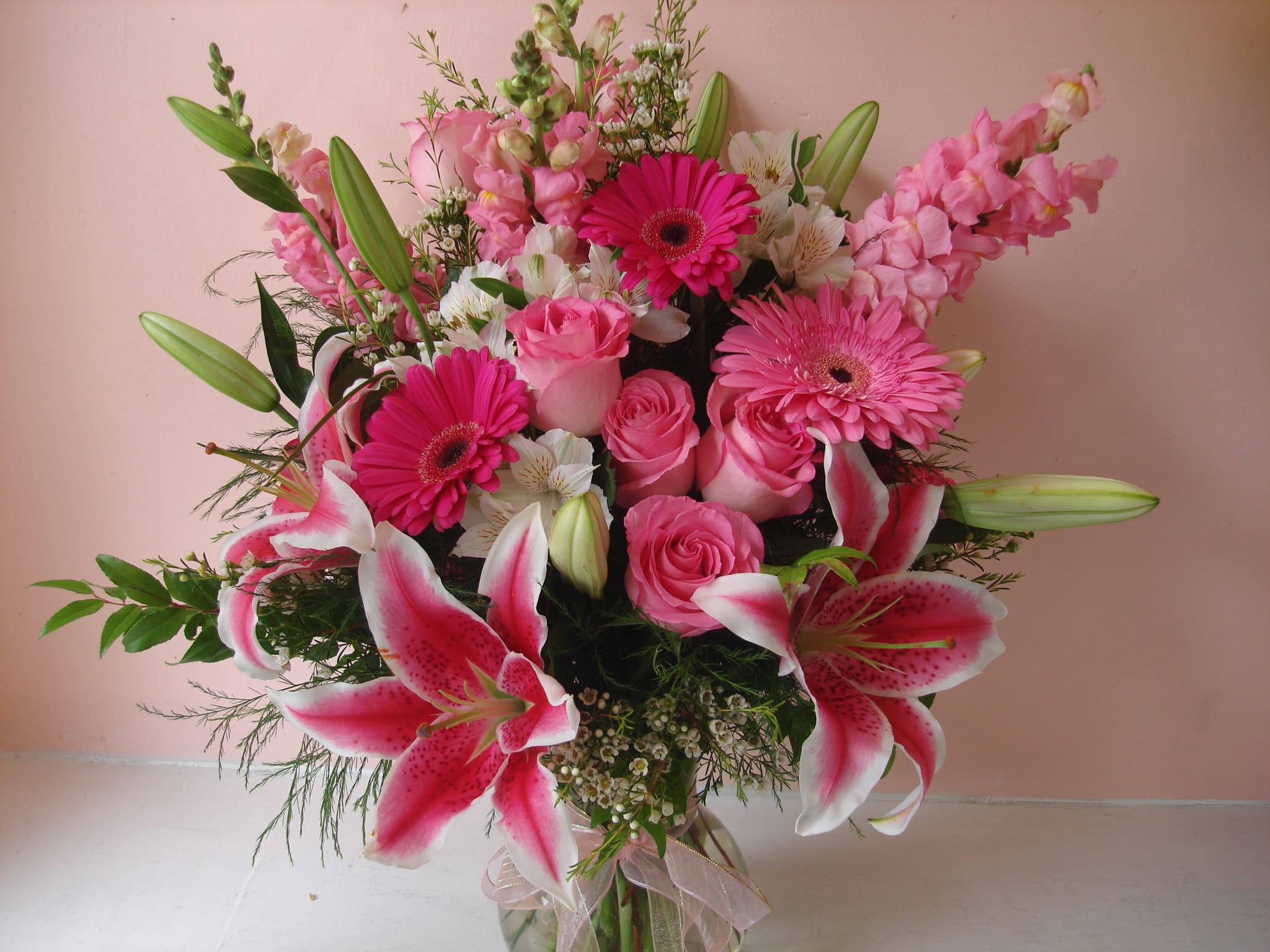 Pink bouquet with lilies, roses, and gerbera daisies in a glass vase