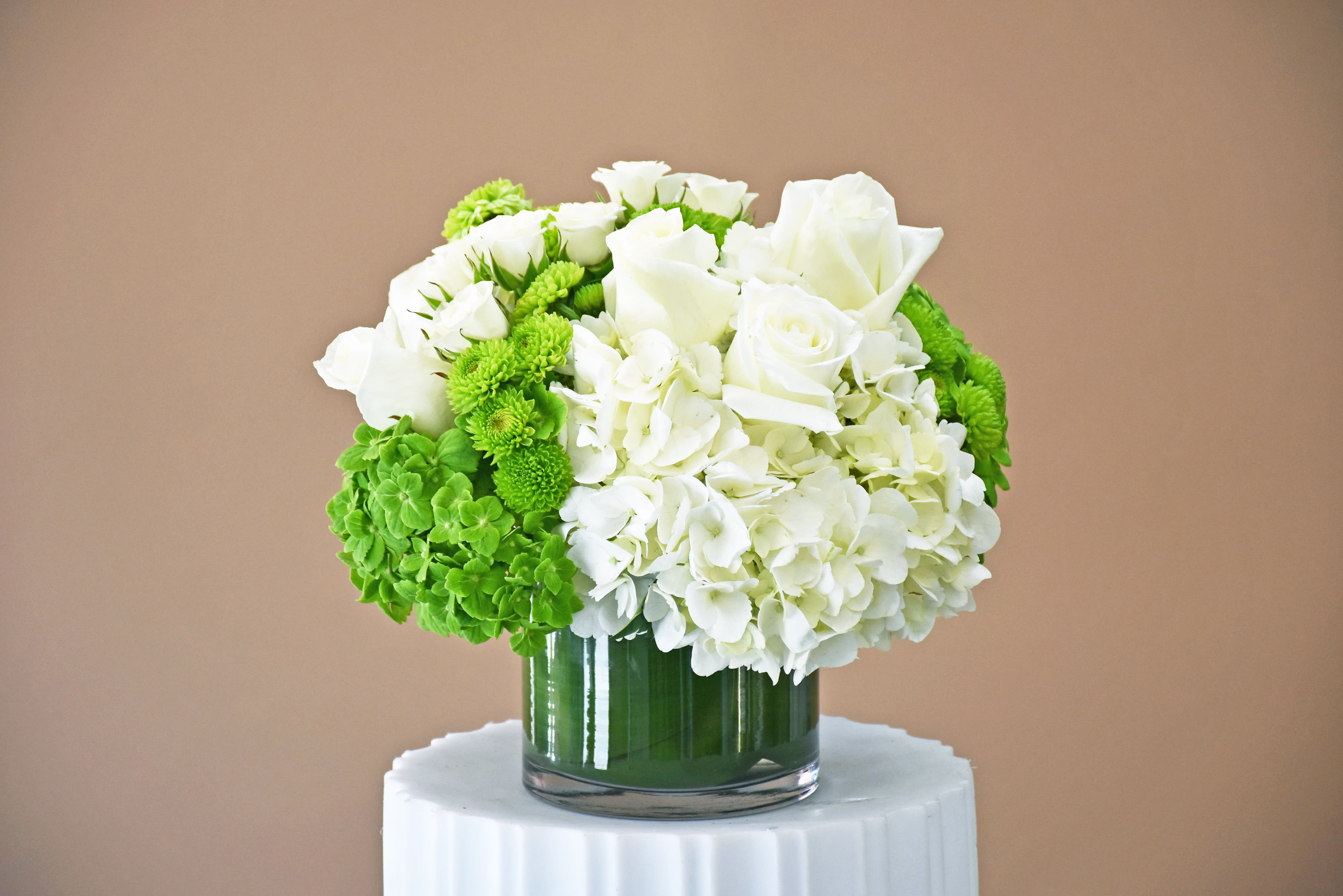White roses and hydrangeas with green mums in a glass vase
