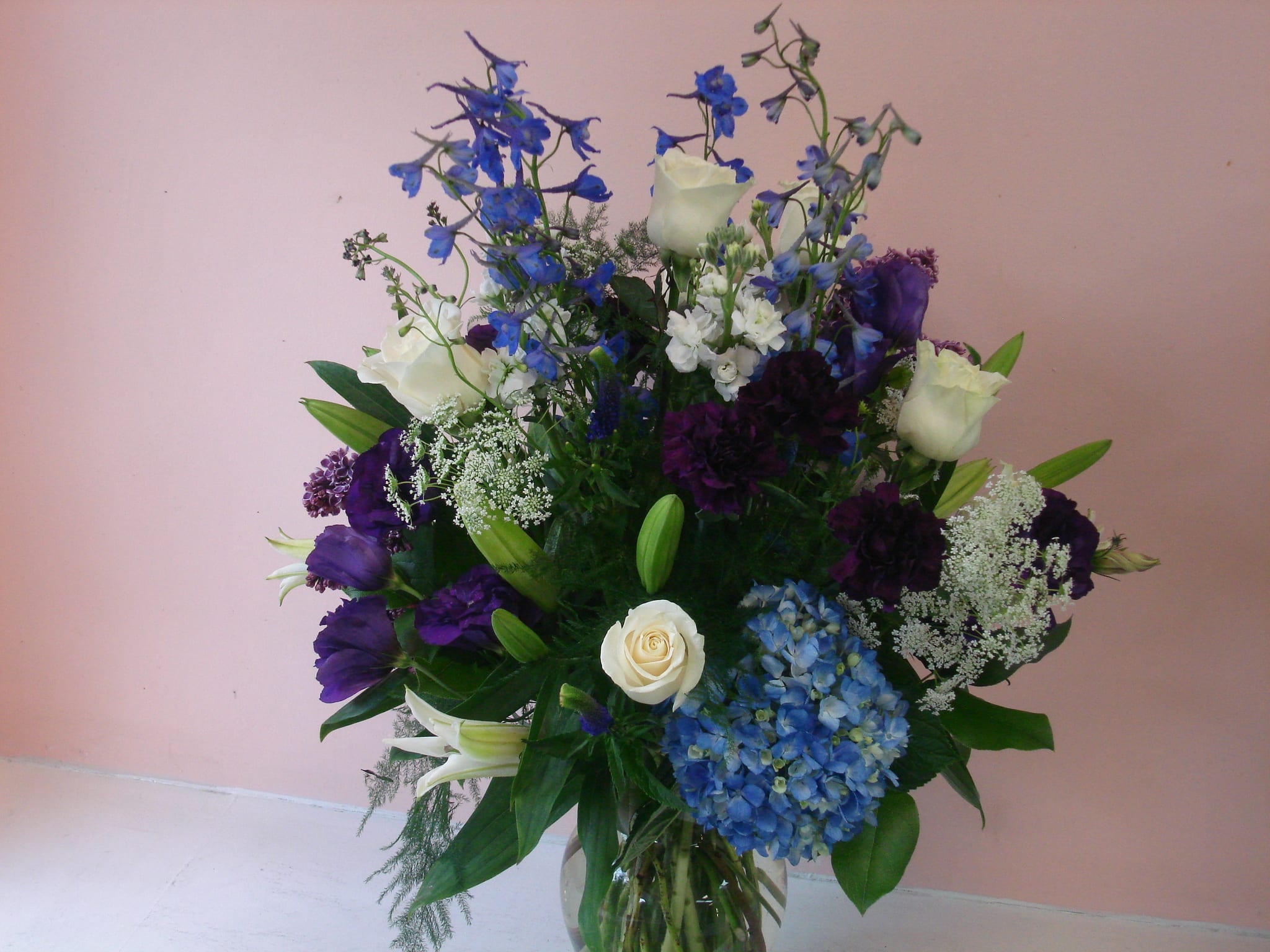 Bouquet of blue, white, and purple flowers in a glass vase