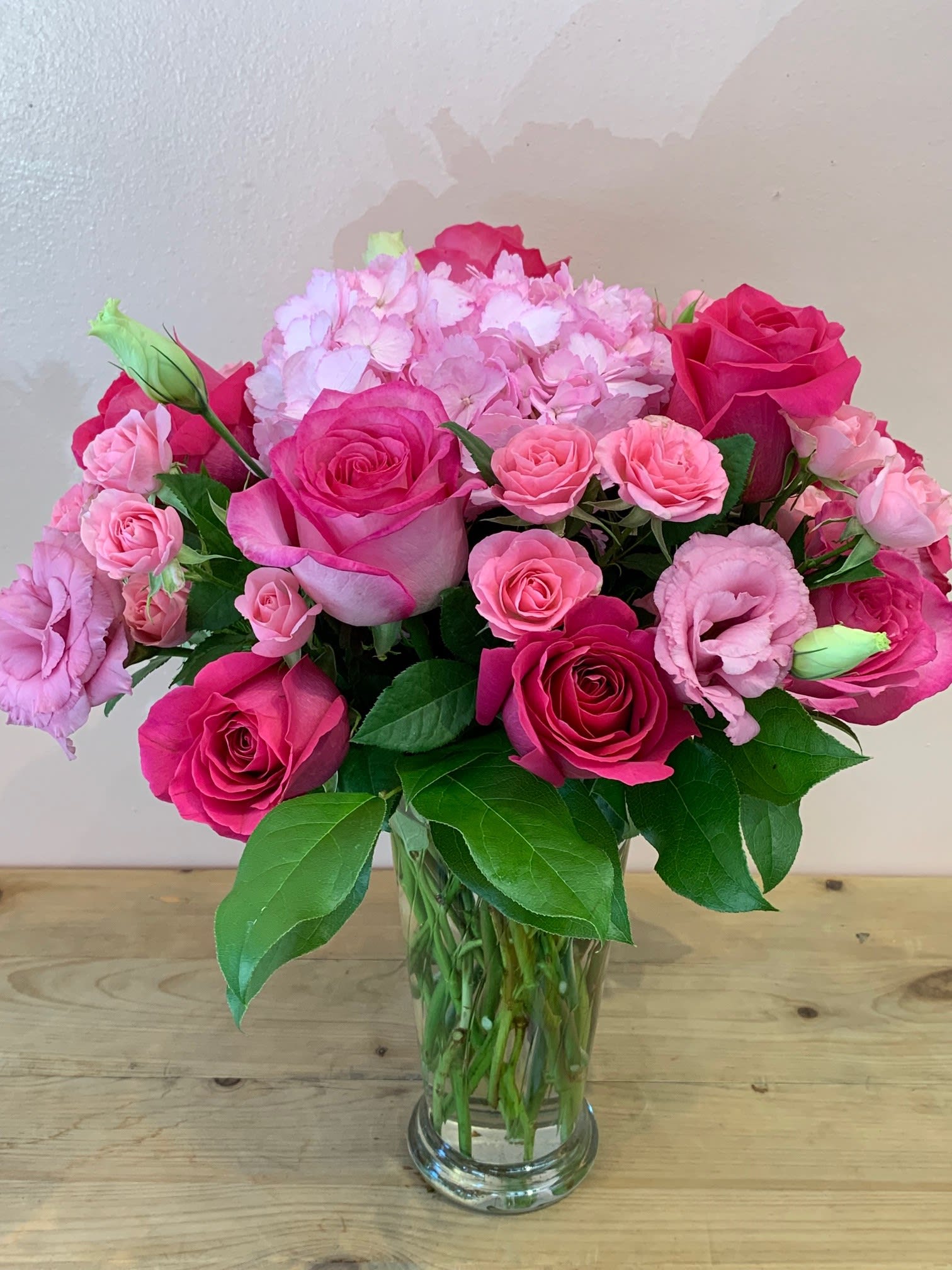 Pink roses and lisianthus arranged in a clear glass vase
