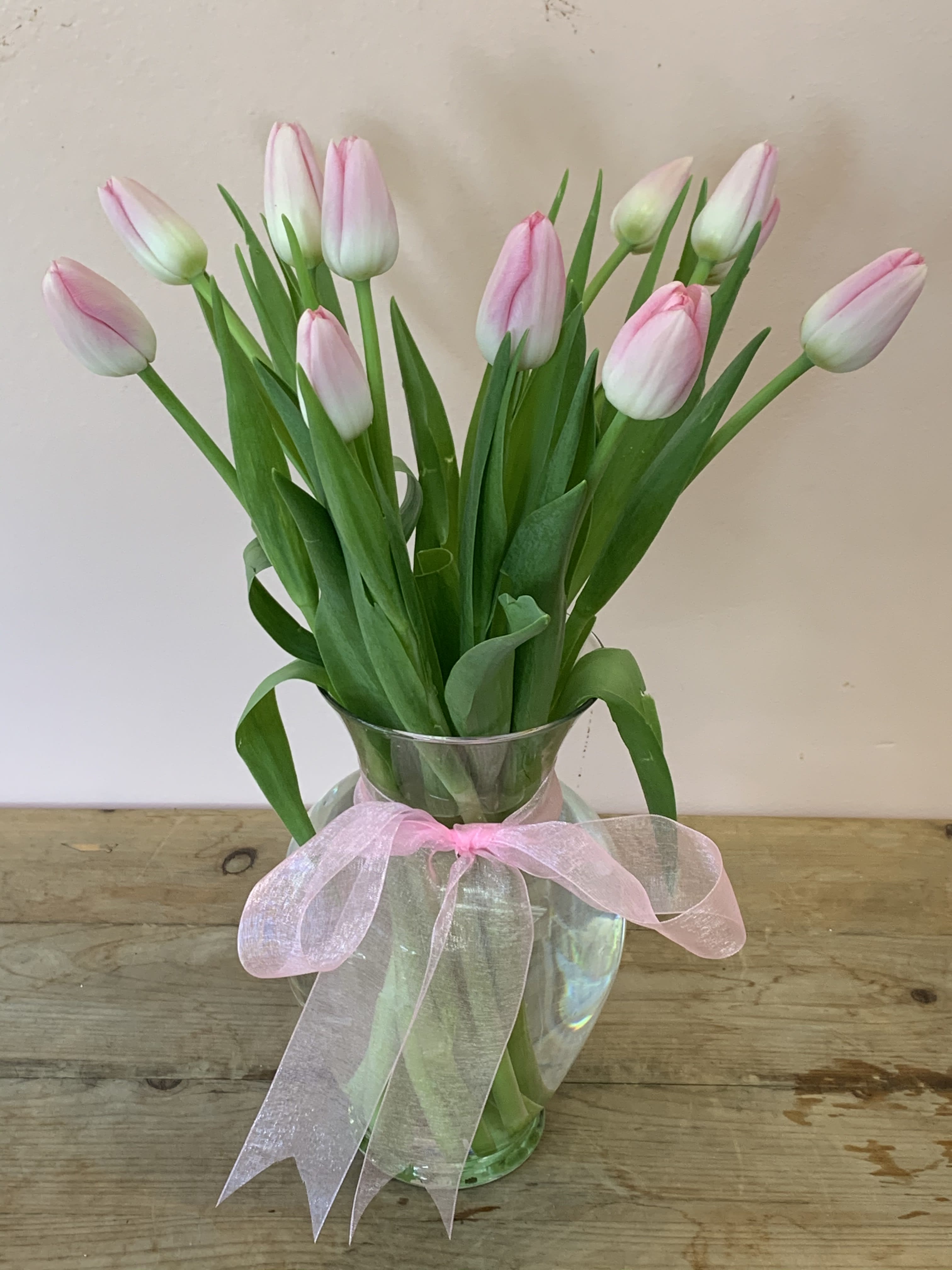 Pink tulips in a clear glass vase tied with a pink ribbon
