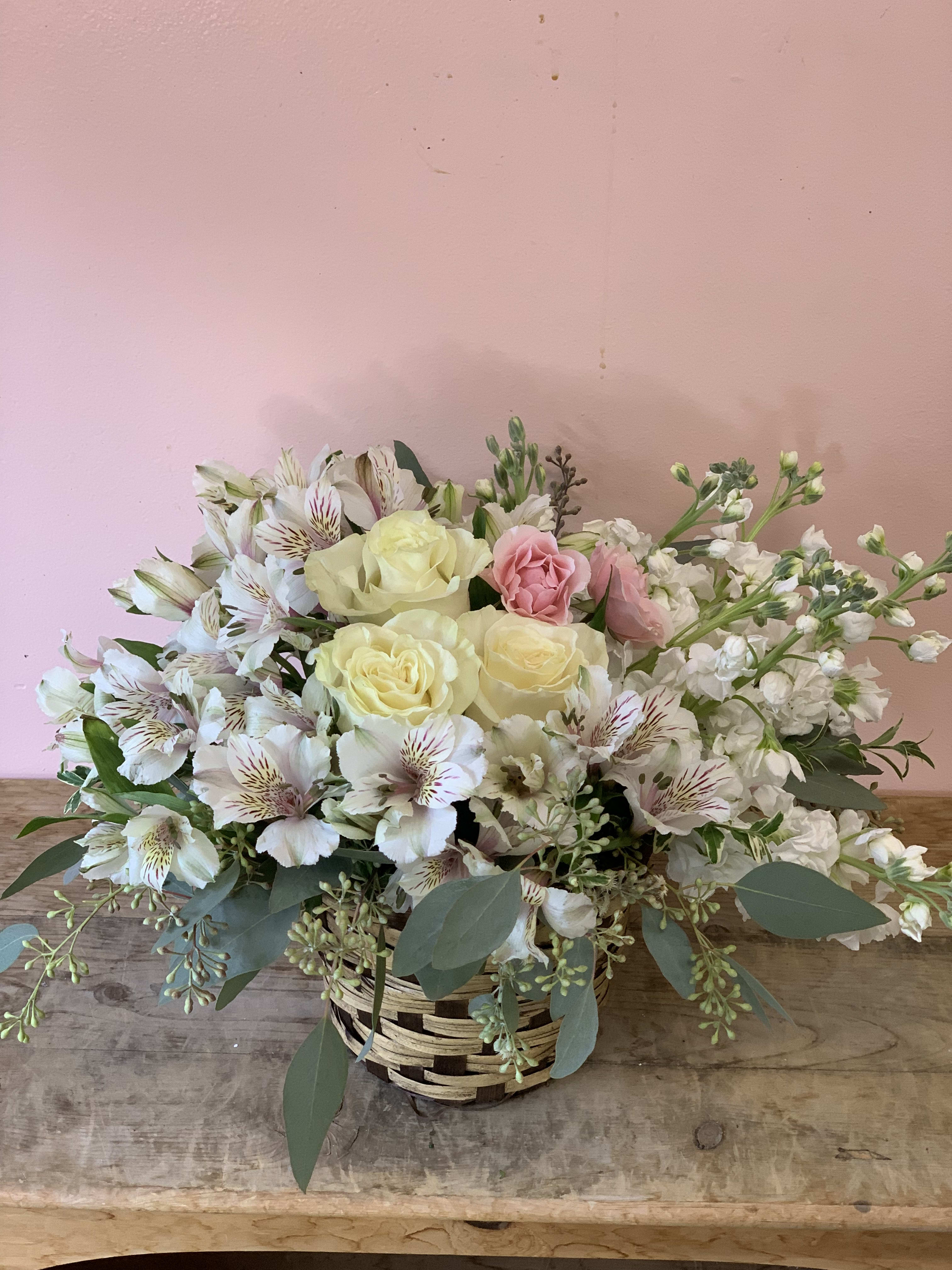 Basket arrangement of pale roses, white alstroemeria, and pink blooms