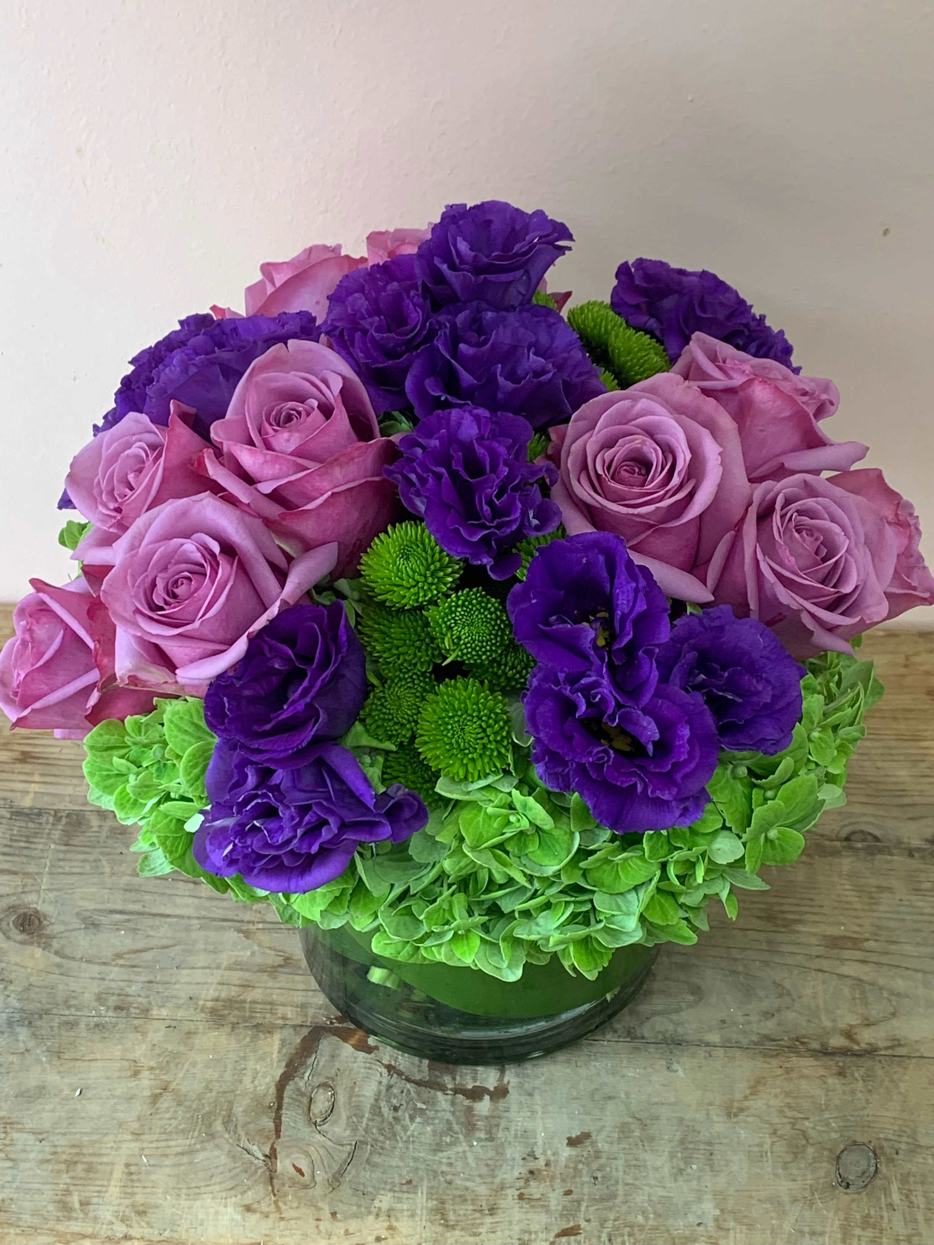 Purple and pink roses with green chrysanthemums in a glass vase