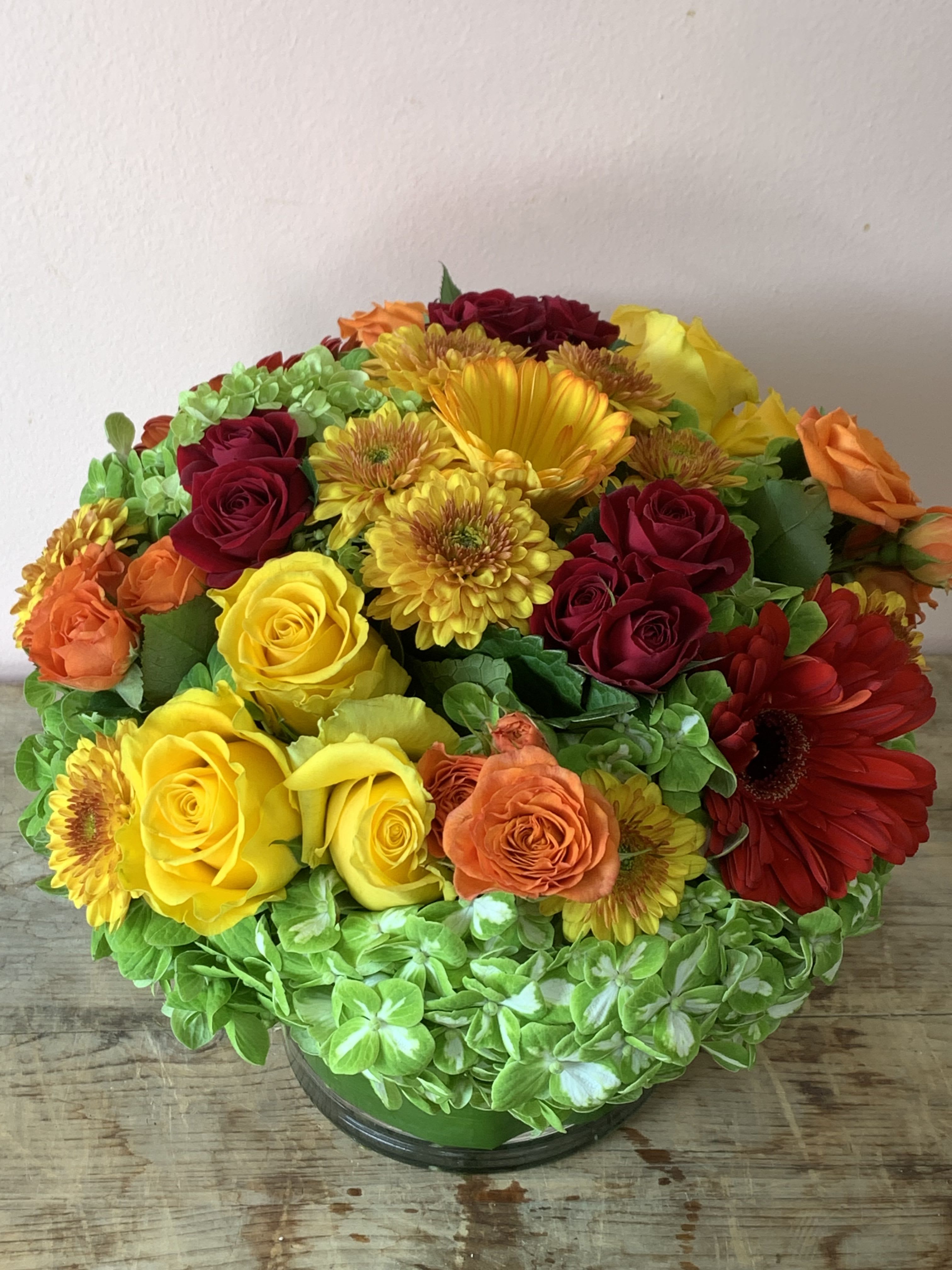 Mixed bouquet of roses, gerbera daisies, and chrysanthemums in a glass vase