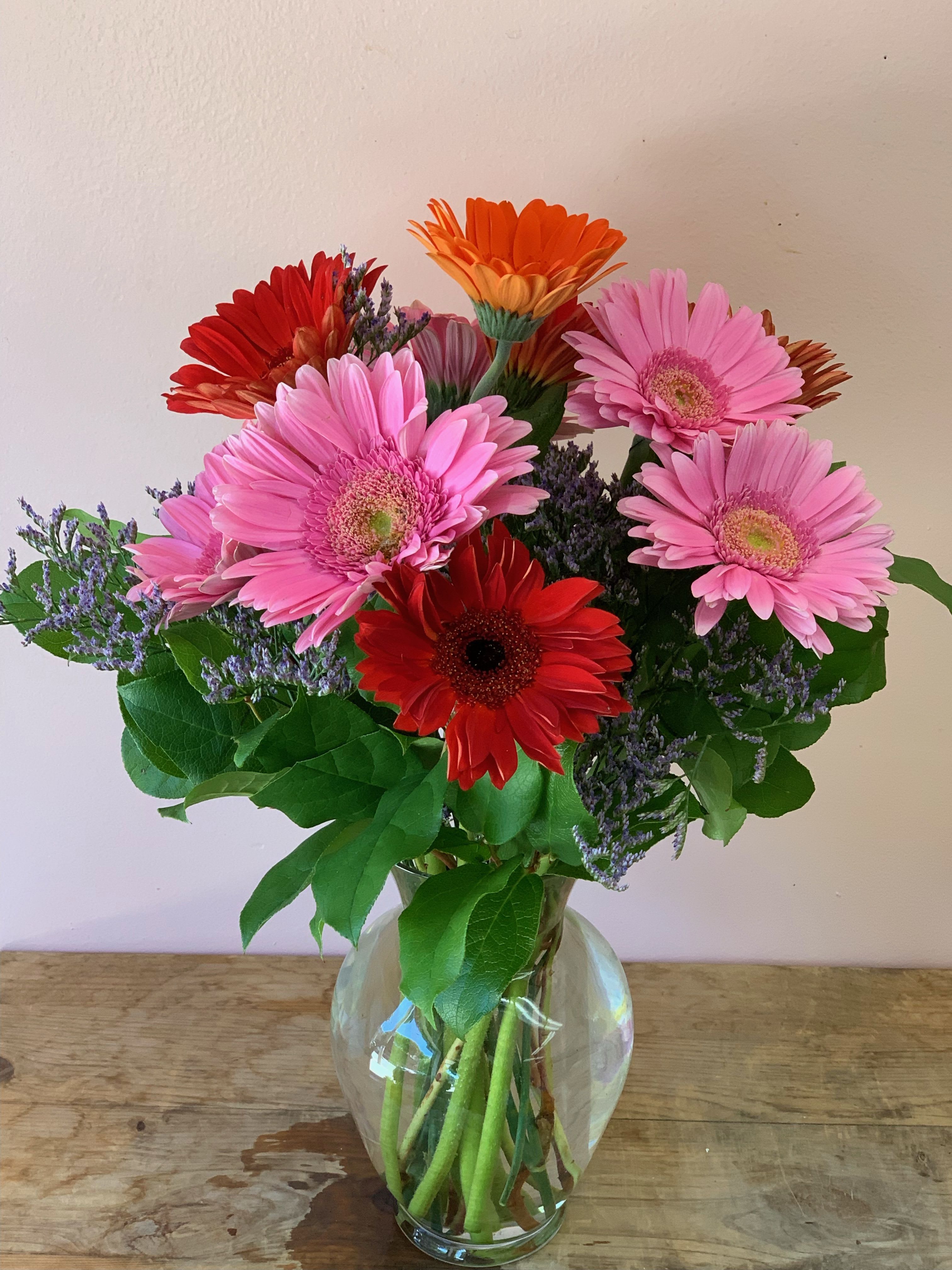 Bouquet of pink, red, and orange gerbera daisies in a glass vase