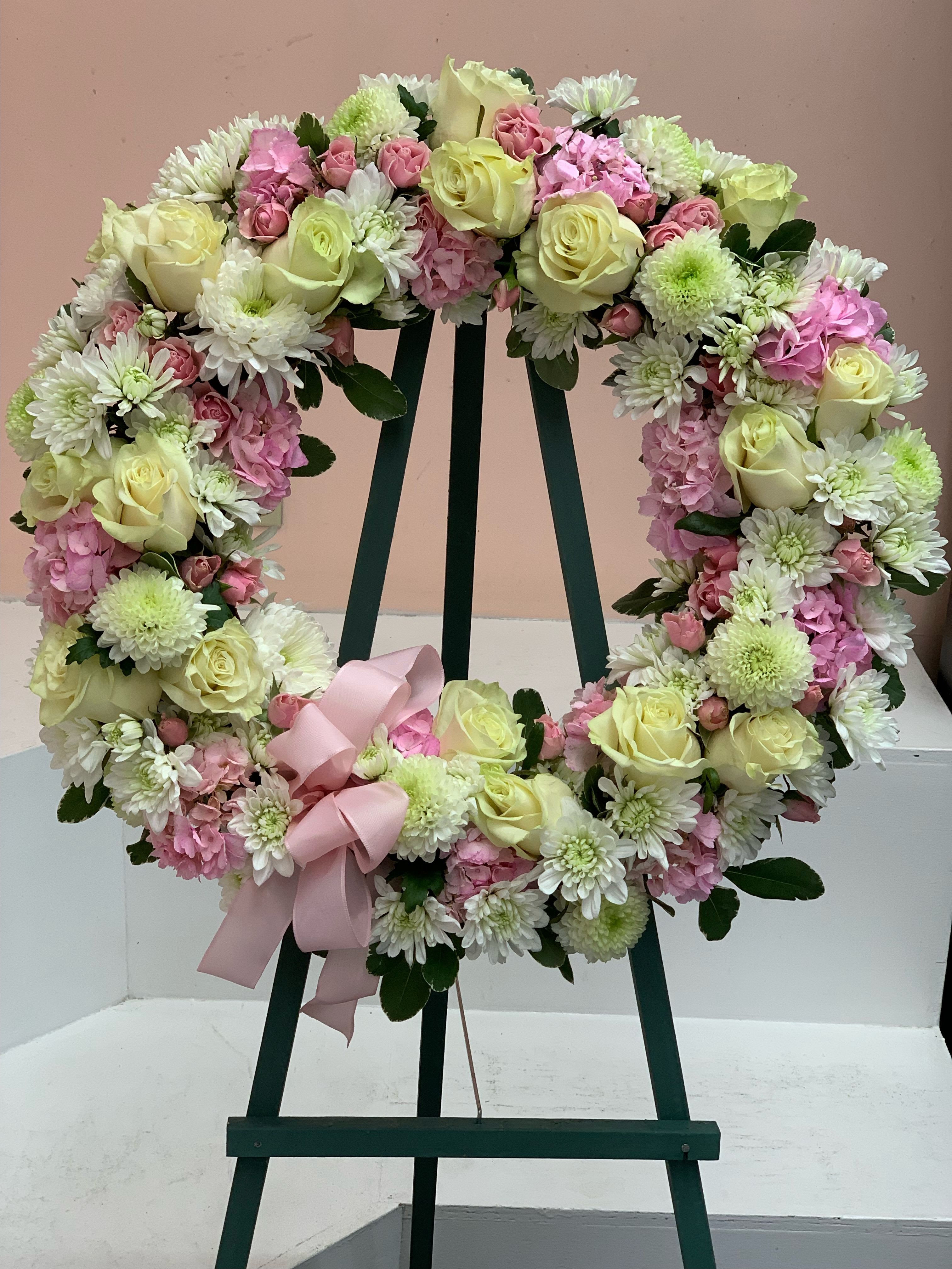 Heart-shaped floral wreath with pale roses, pink blooms, and a pink ribbon